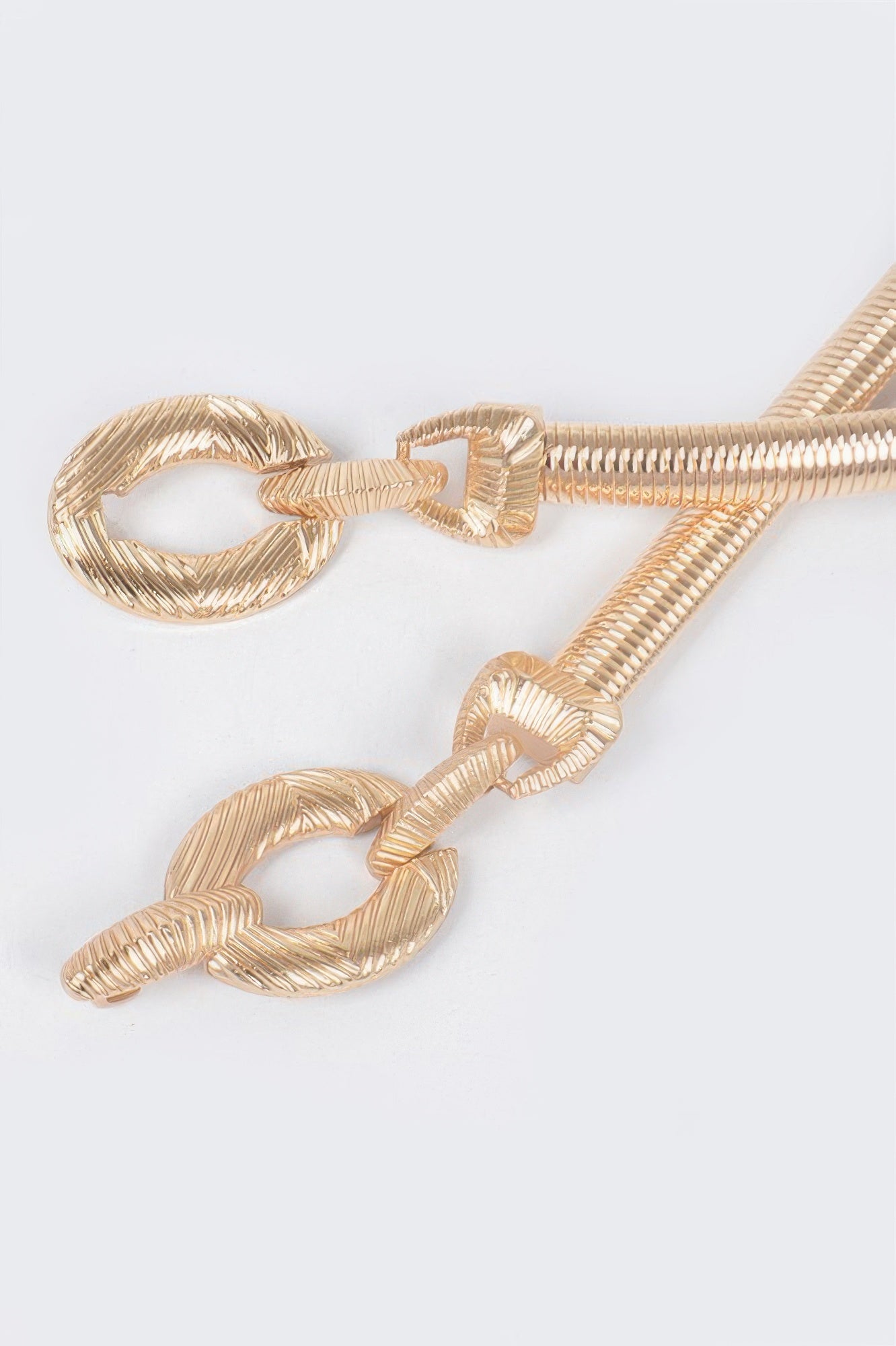 Gold-tone metal stretch belt close-up: braided segments and oval rings