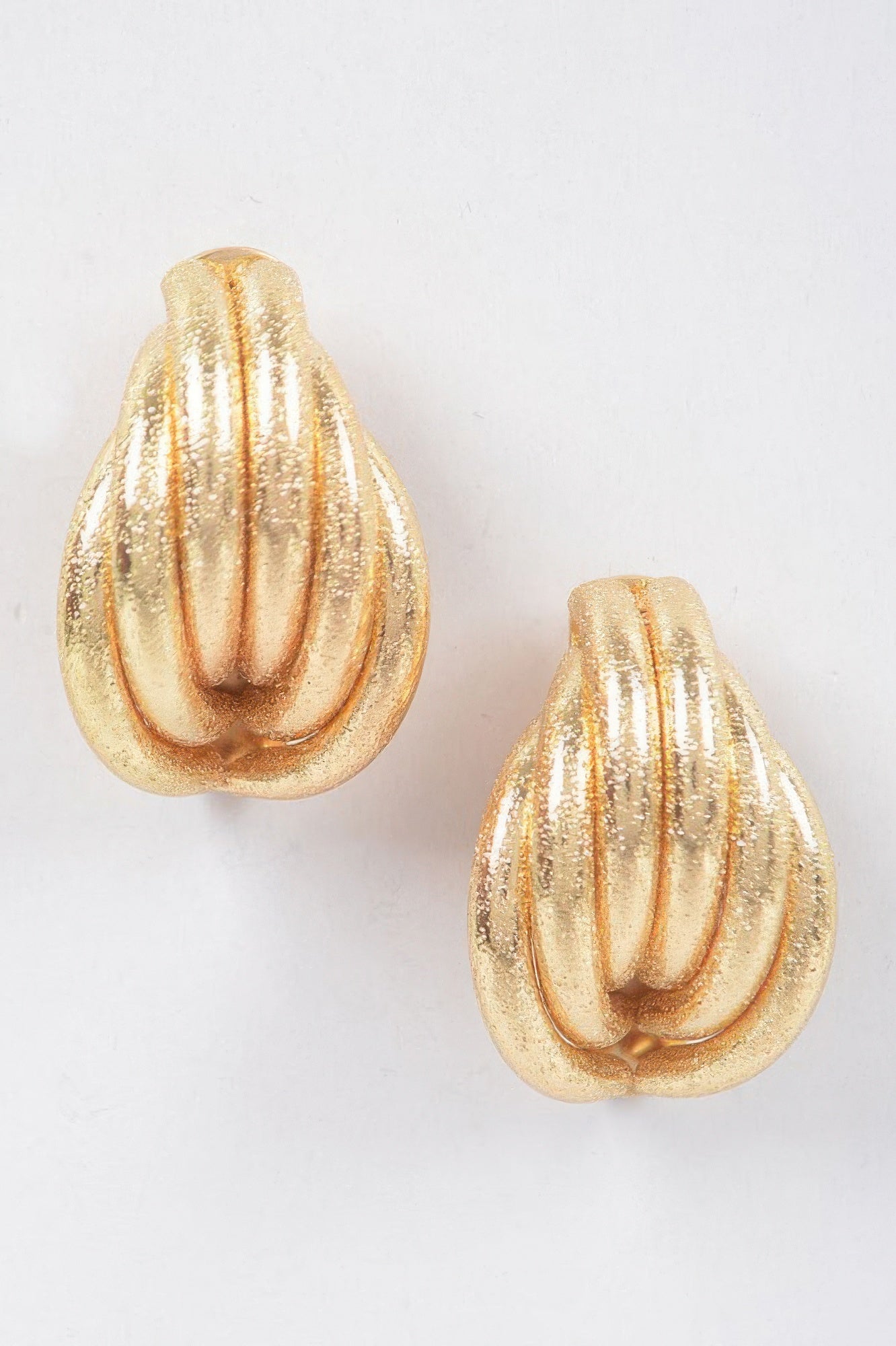 Gold metal stud earrings, teardrop shape with ridged swirl texture