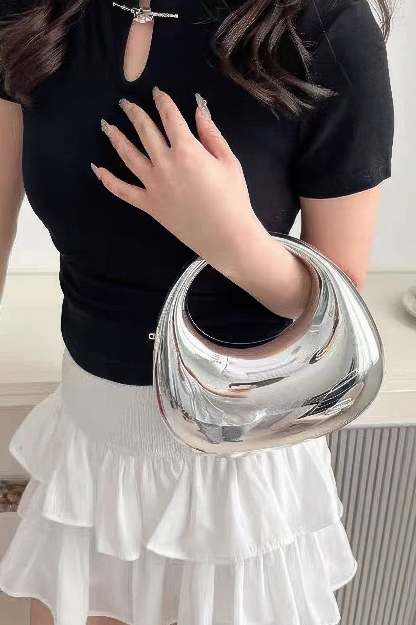 Metallic acrylic clutch with glossy silver finish, held in hand