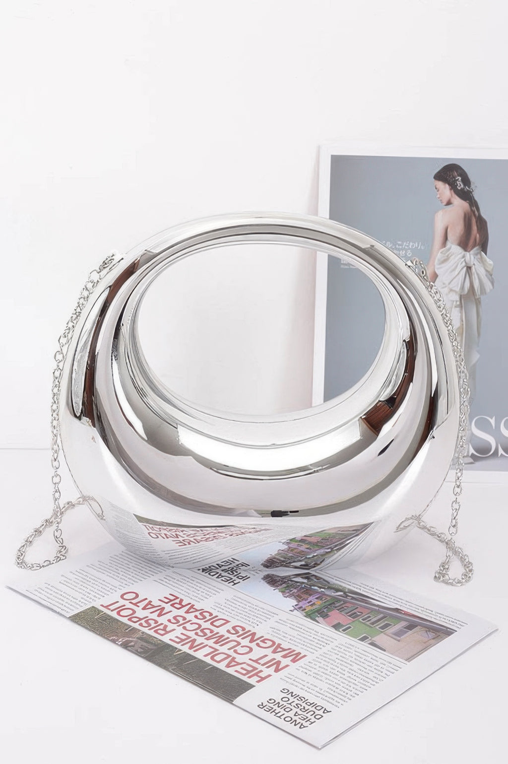 Metallic acrylic clutch with chain strap and rounded mirrored surface