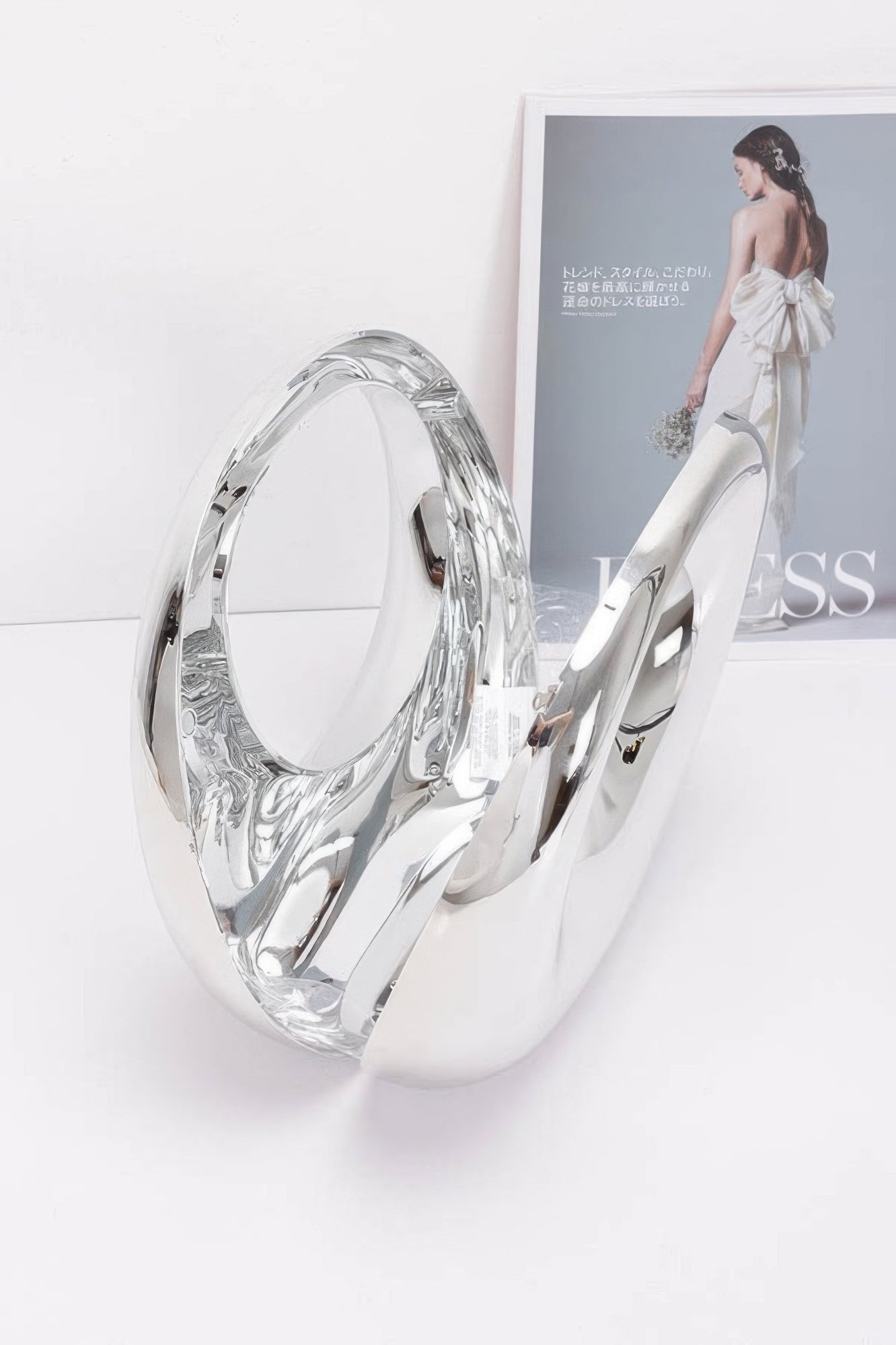 Metallic acrylic clutch in mirrored silver, angled side view