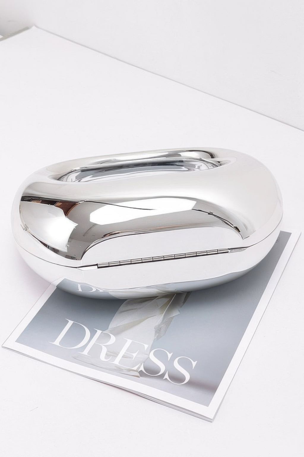 Metallic acrylic clutch with reflective silver top and curved shape