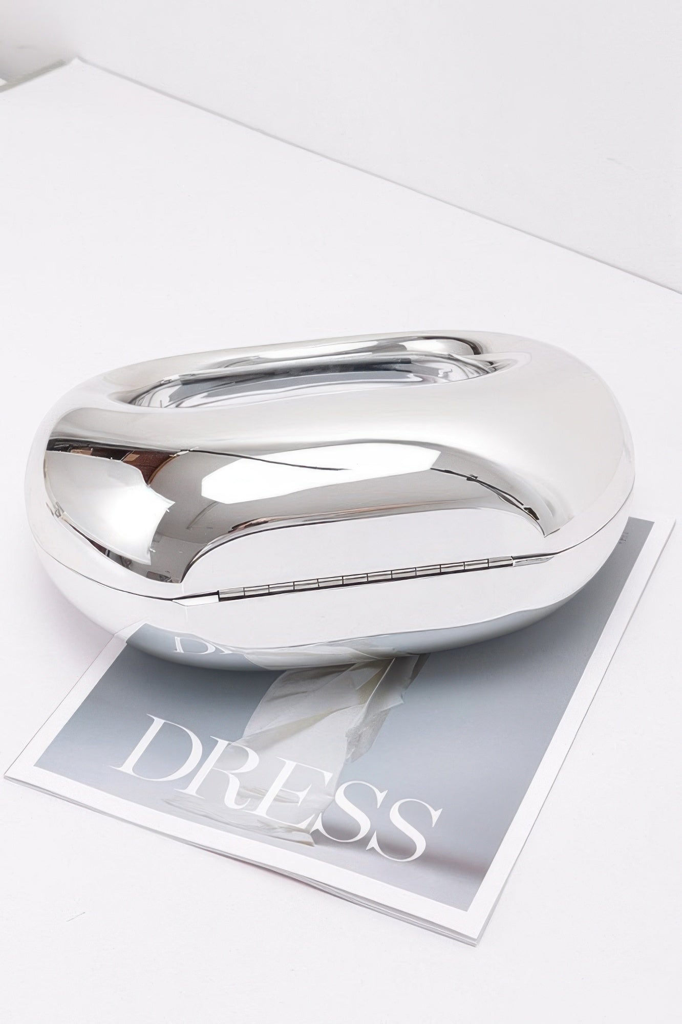 Metallic acrylic clutch with reflective silver top and curved shape