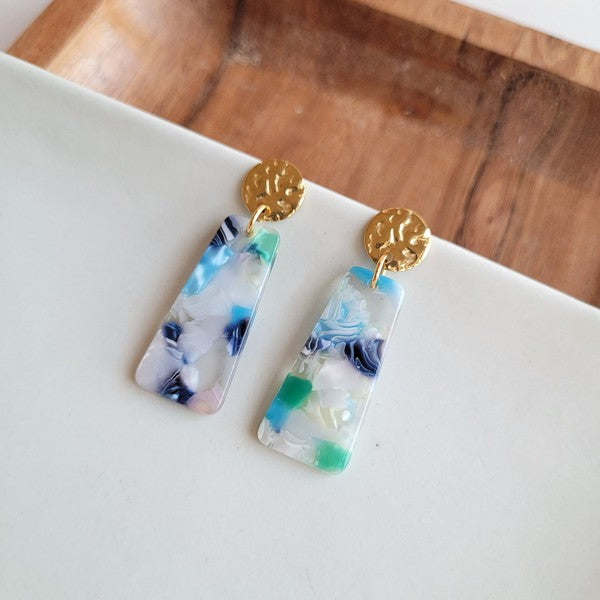 Mini earrings close-up: gold stud caps with clear resin blocks and colorful embedded pieces