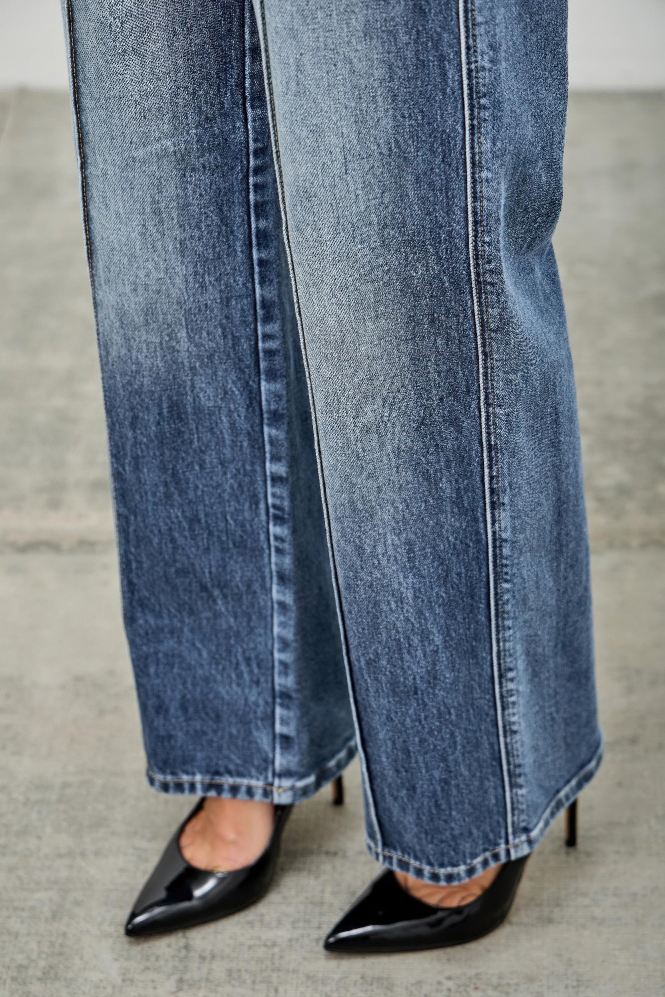 Close-up of blue straight jean legs with pintuck seam and stitched hem