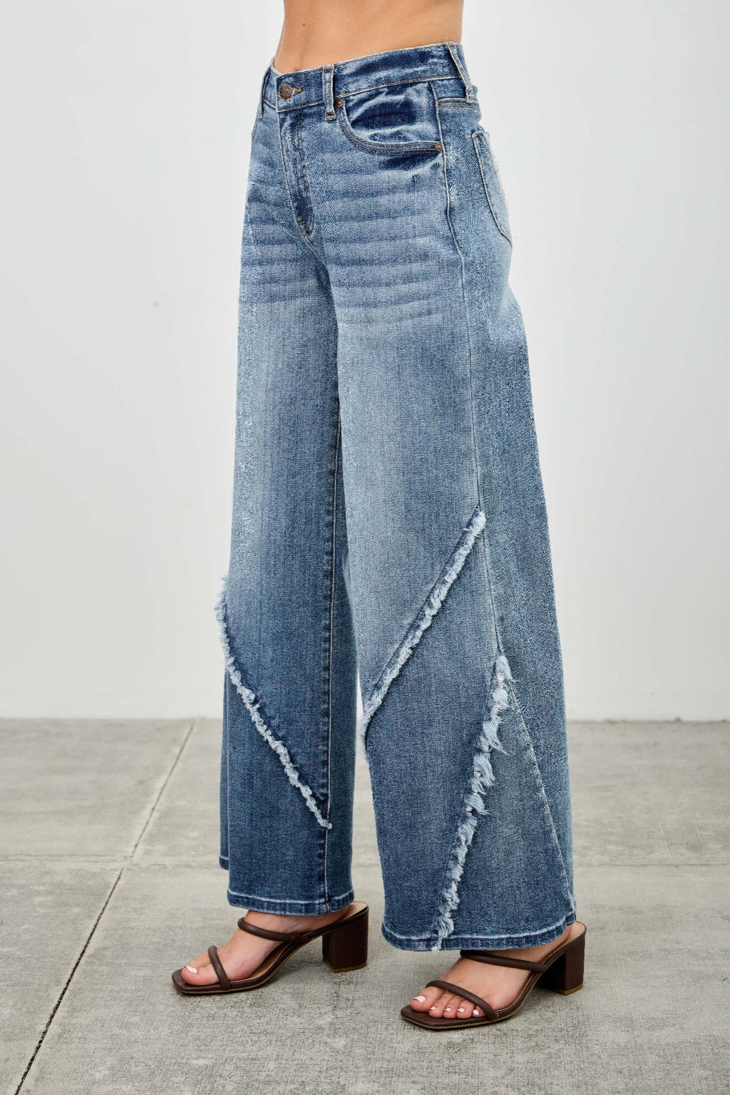 Back view: light wash wide-leg jeans with diagonal frayed seam and rear patch pocket