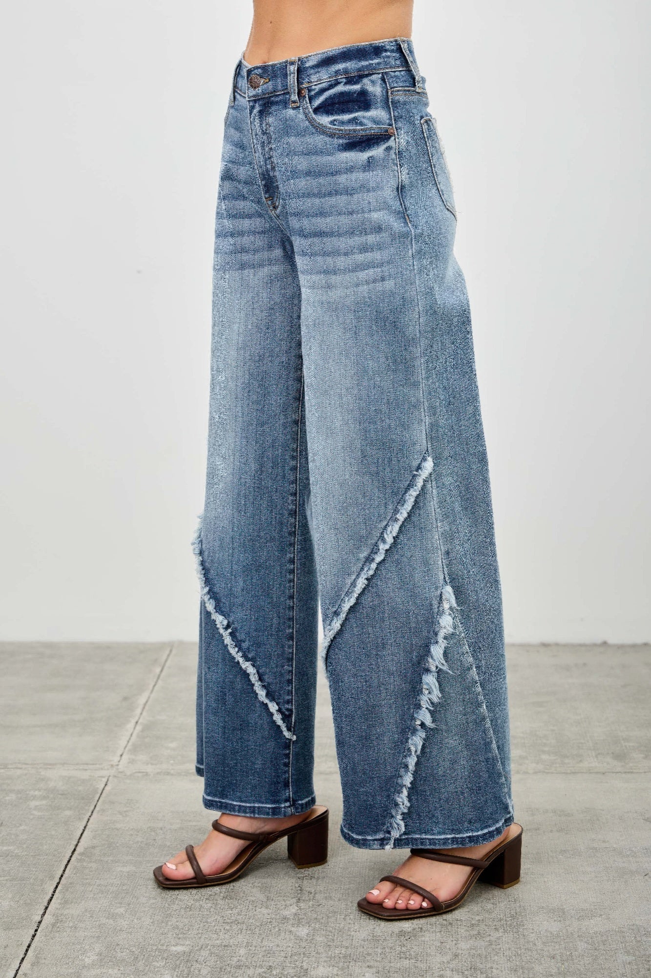 Back view: light wash wide-leg jeans with diagonal frayed seam and rear patch pocket