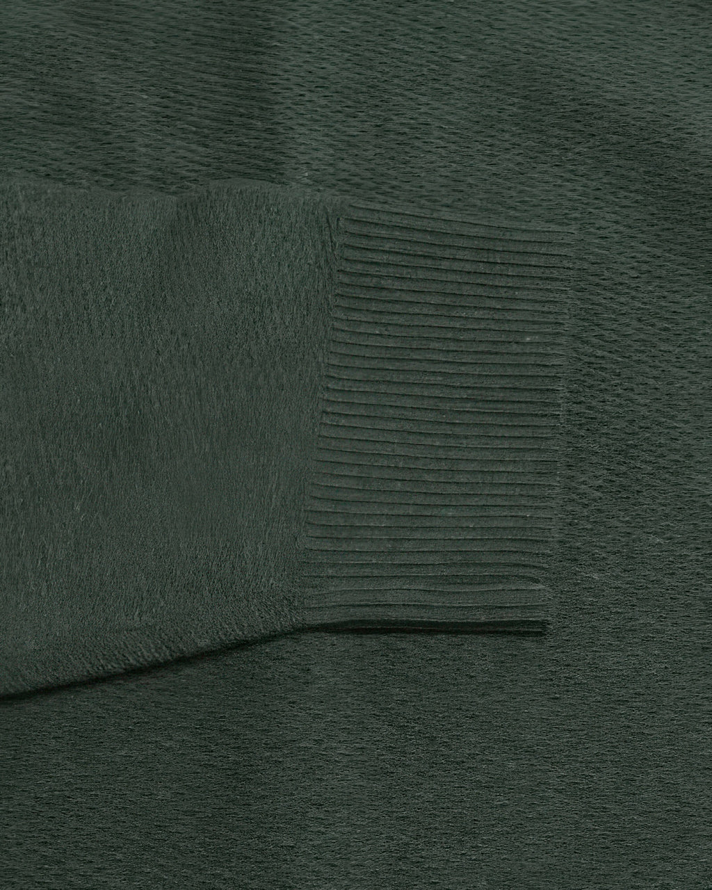 Dark green knit sweater fabric close-up with ribbed panel texture