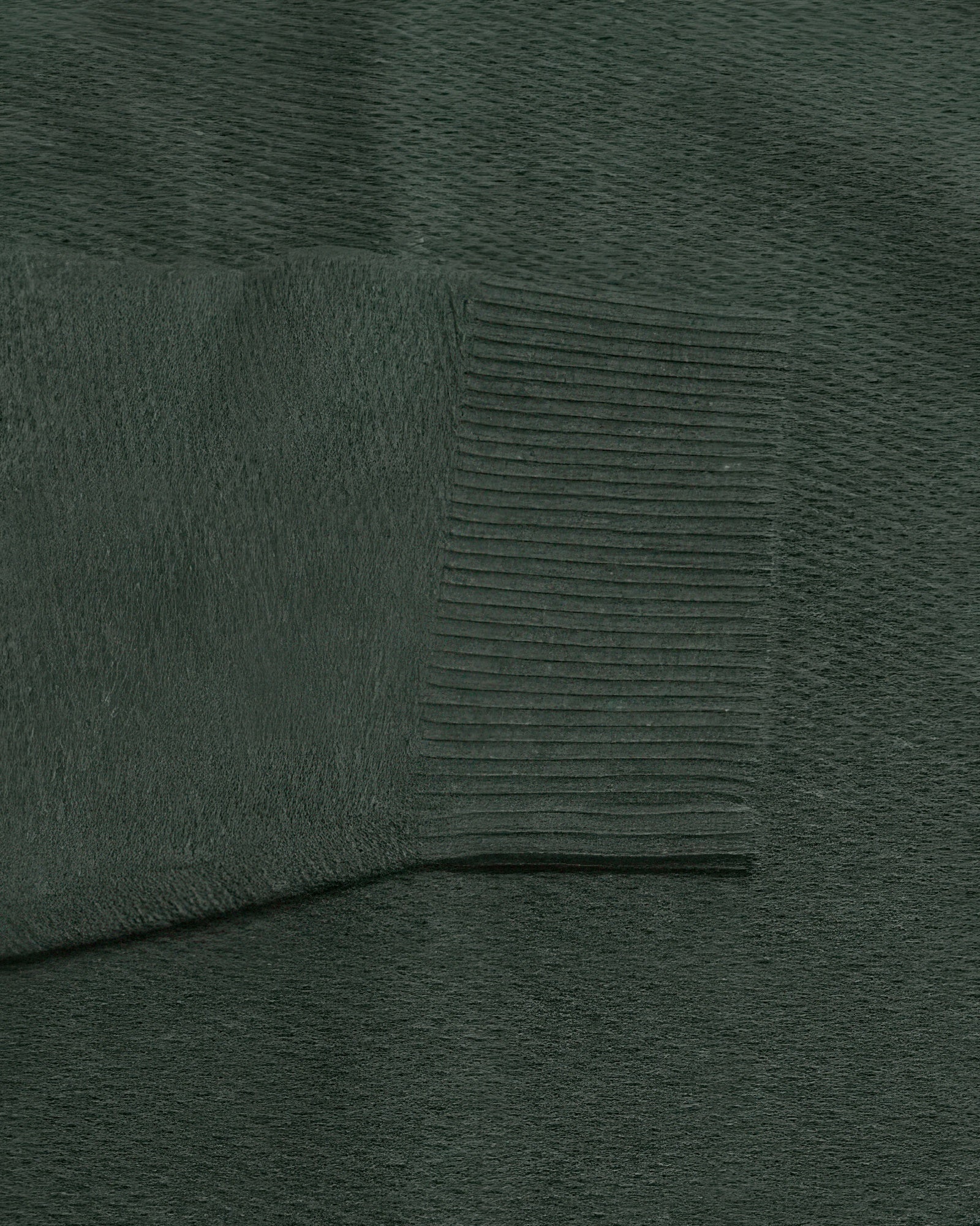 Dark green knit sweater fabric close-up with ribbed panel texture