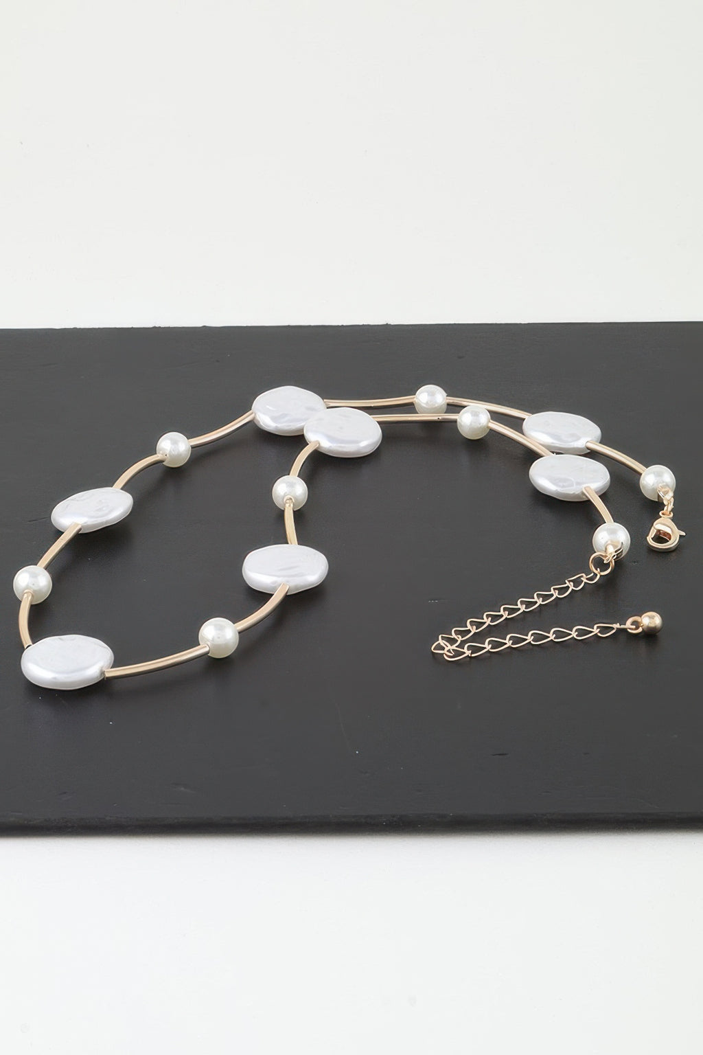 Verstellkettchen am Verschluss der goldfarbenen Charm-Kette mit weißen ovalen Steinen
