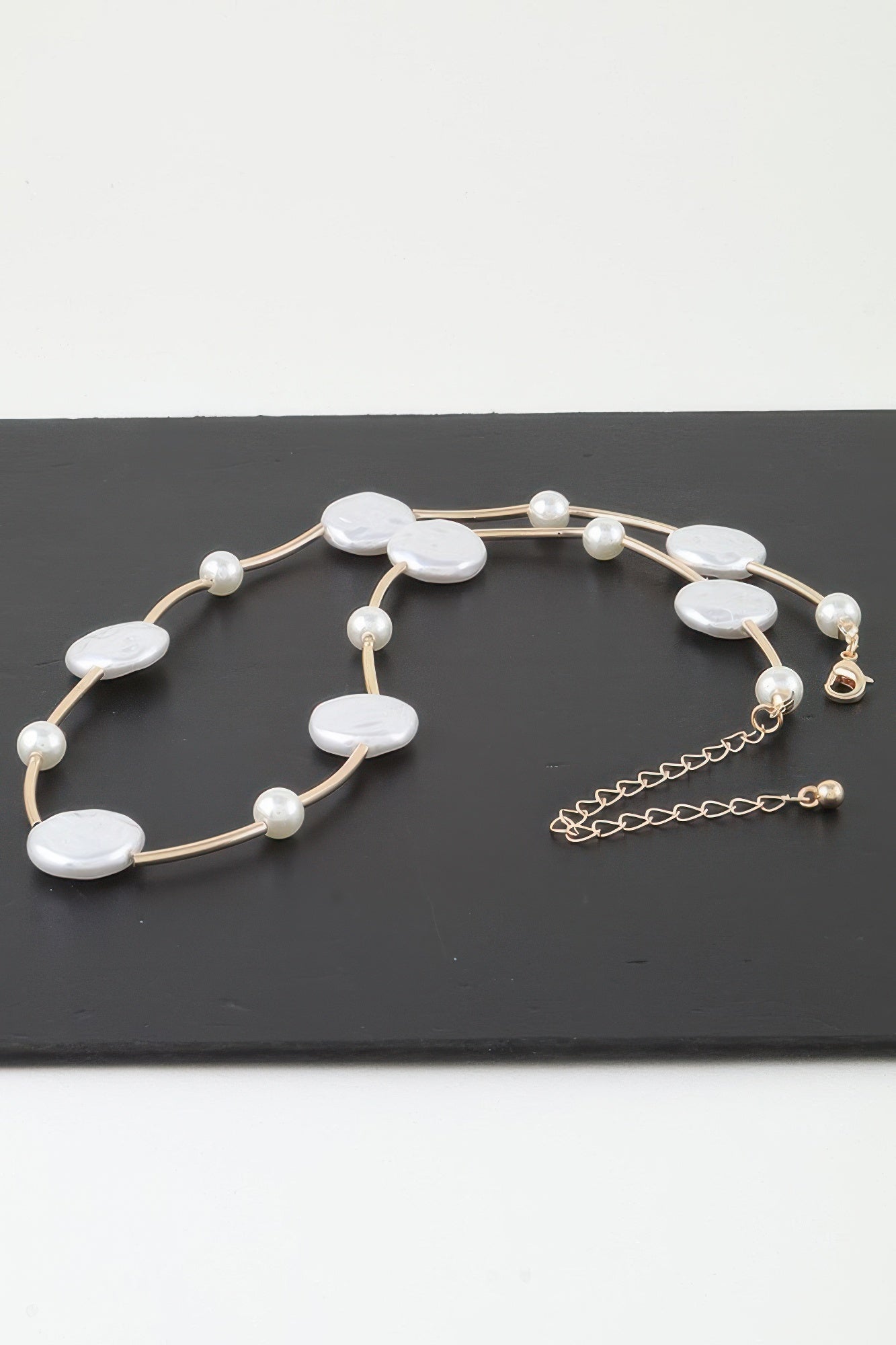 Verstellkettchen am Verschluss der goldfarbenen Charm-Kette mit weißen ovalen Steinen