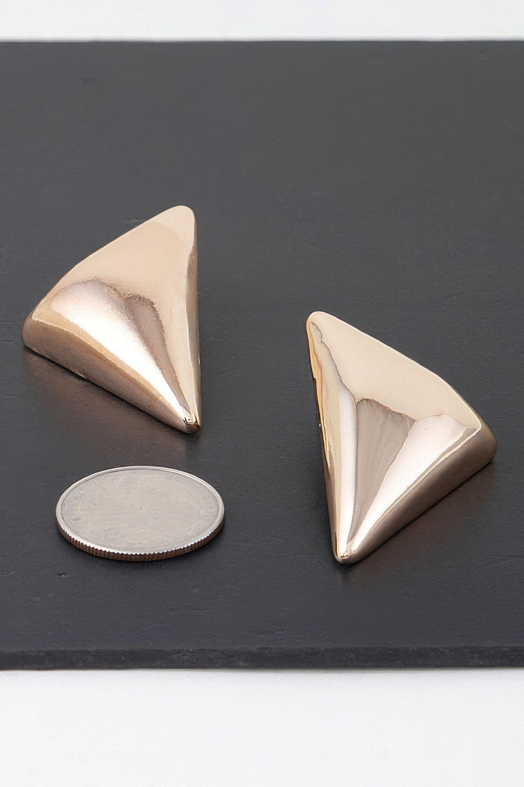Triangular stud earrings, gold-tone metal, polished faceted front