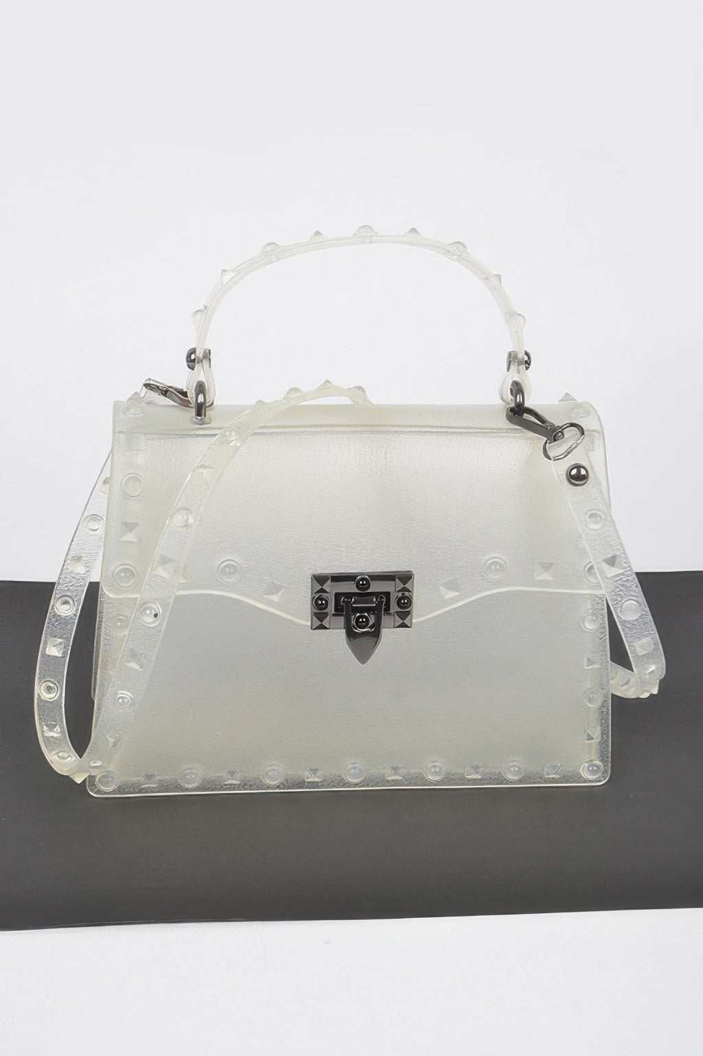 Monotone studded clutch in white with black gem-lock clasp and studded handle straps