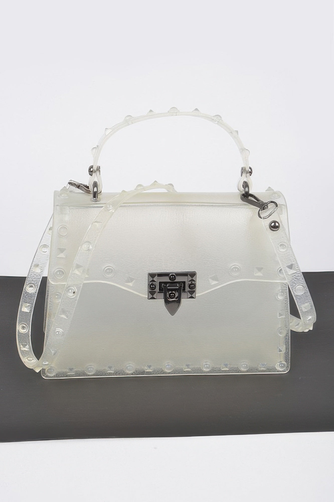 Monotone studded clutch in white with black gem-lock clasp and studded handle straps