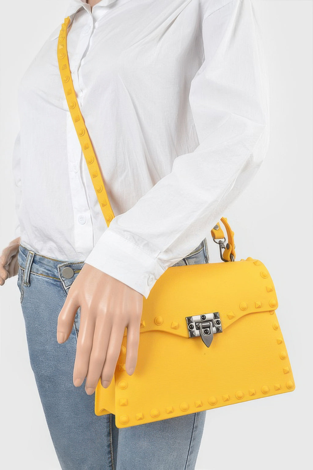 Yellow studded clutch worn crossbody, front lock detail and short top handle