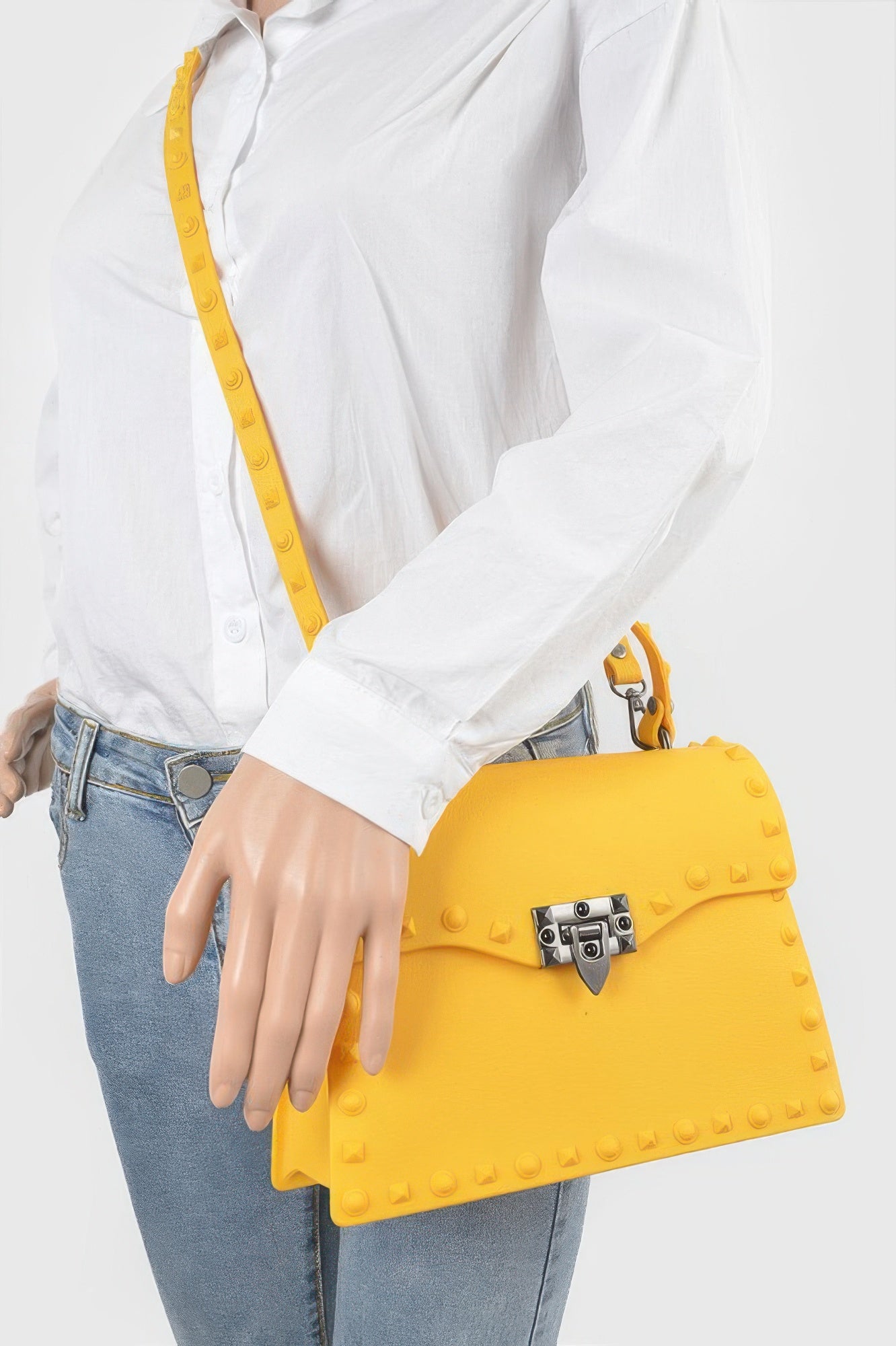 Yellow studded clutch worn crossbody, front lock detail and short top handle