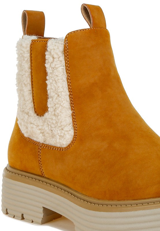 Close-up tan faux-suede ankle boots with cream faux fur insert and stitched seams