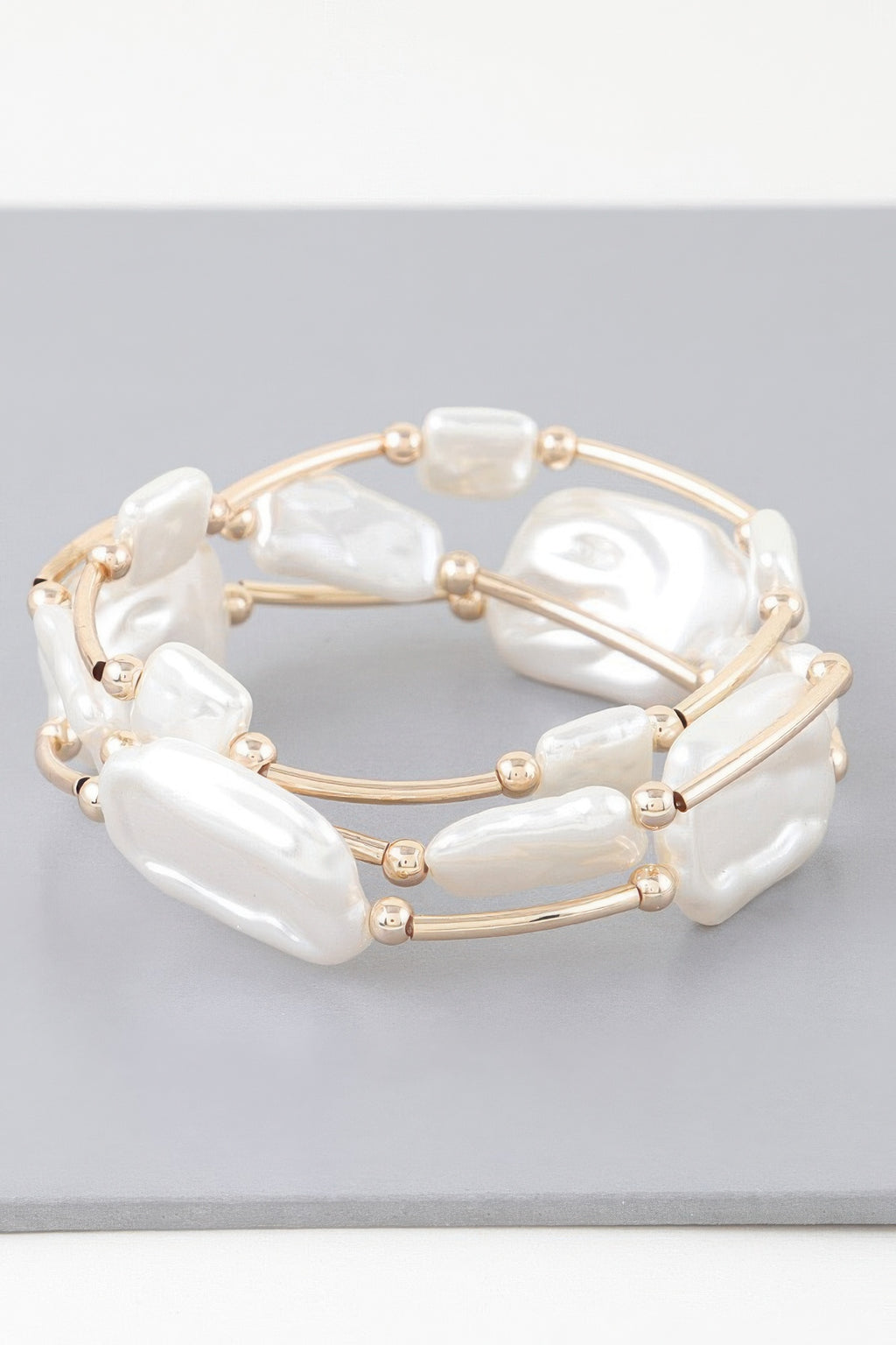 Gold-tone tube bracelet with white irregular pearl stones and small round bead caps