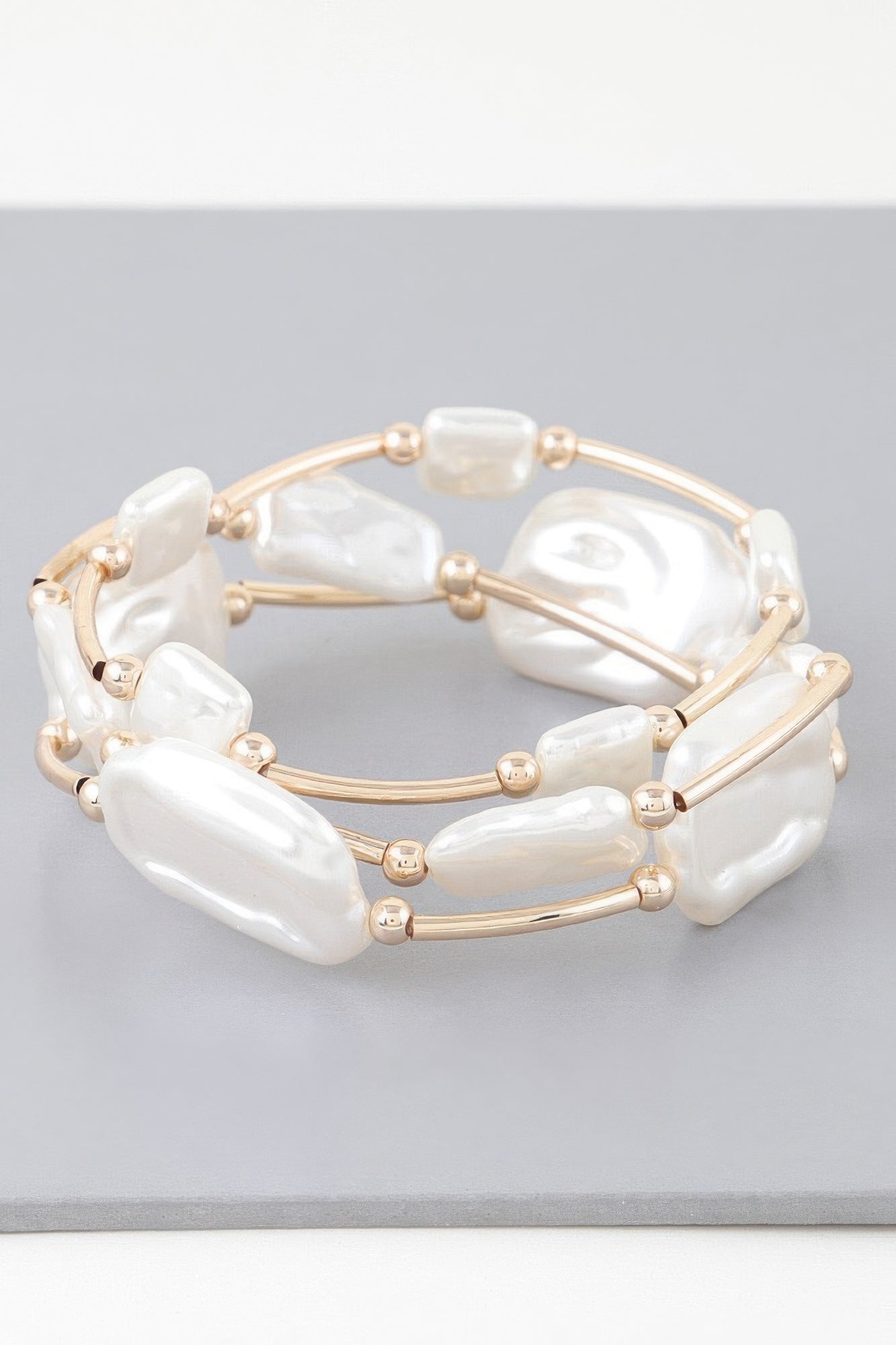 Gold-tone tube bracelet with white irregular pearl stones and small round bead caps