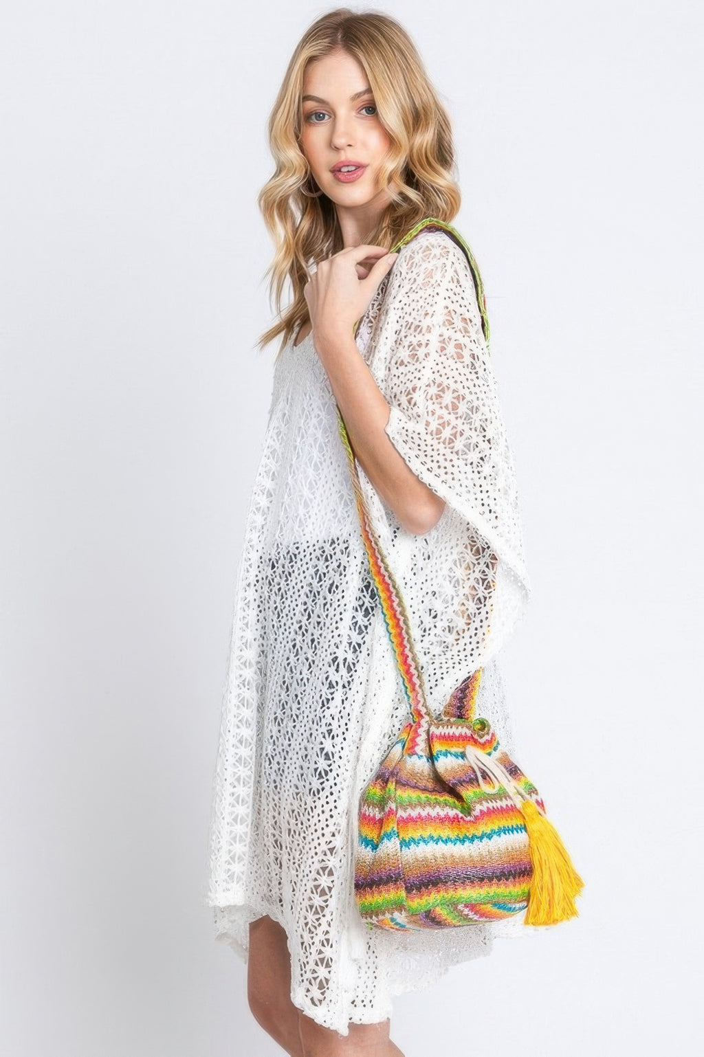 Chevron bucket bag with rainbow stripes and bright yellow tassel, worn crossbody