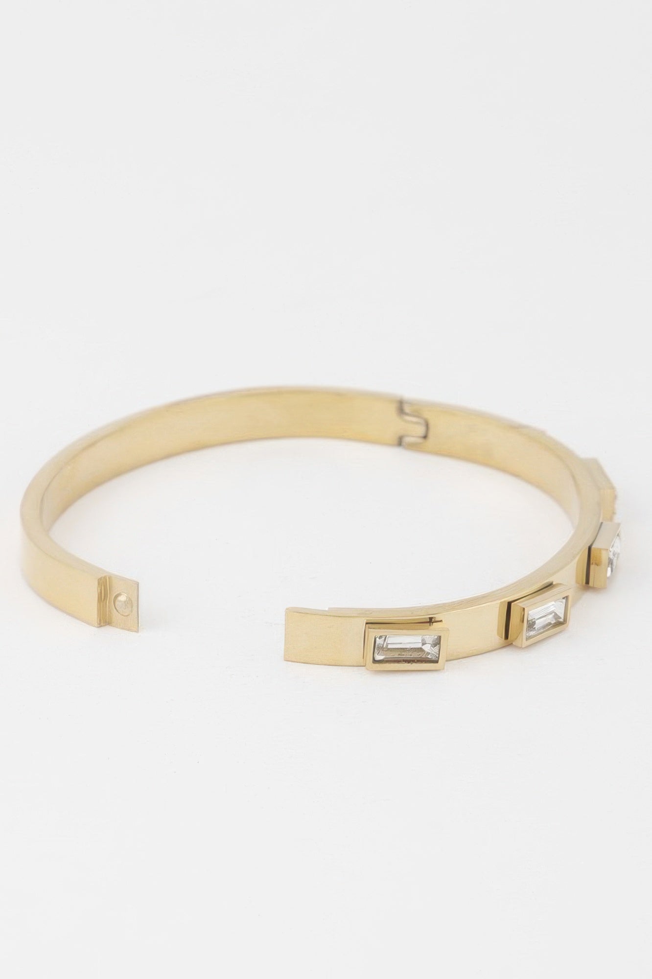 Gold bracelet with hinged clasp and two clear rectangular crystals