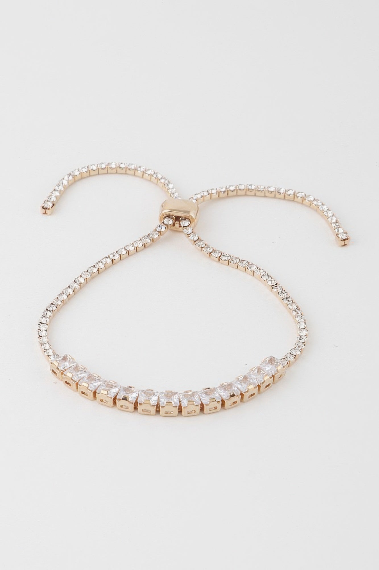 Gold-toned bracelet with clear square cubic stones and a bow-shaped center clasp