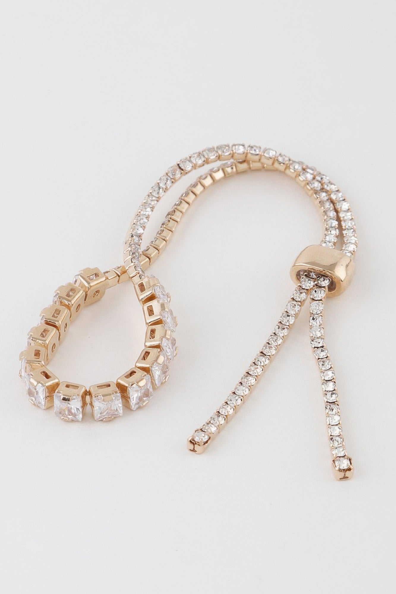 Gold-toned bracelet set with clear square cubic stones, two curved strands, and charm
