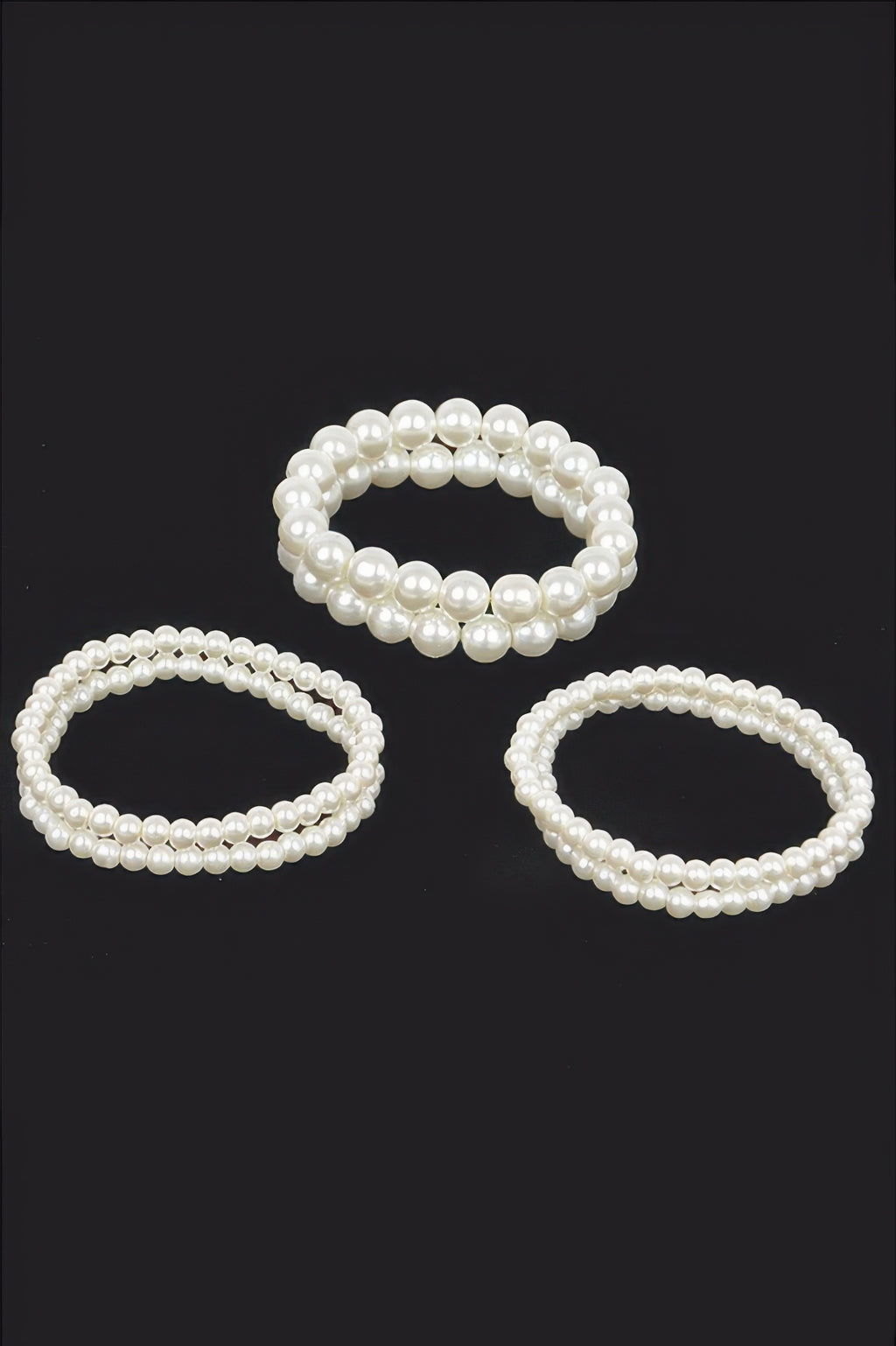 Cream faux pearl stretch bracelets set—three oval loops on a dark background