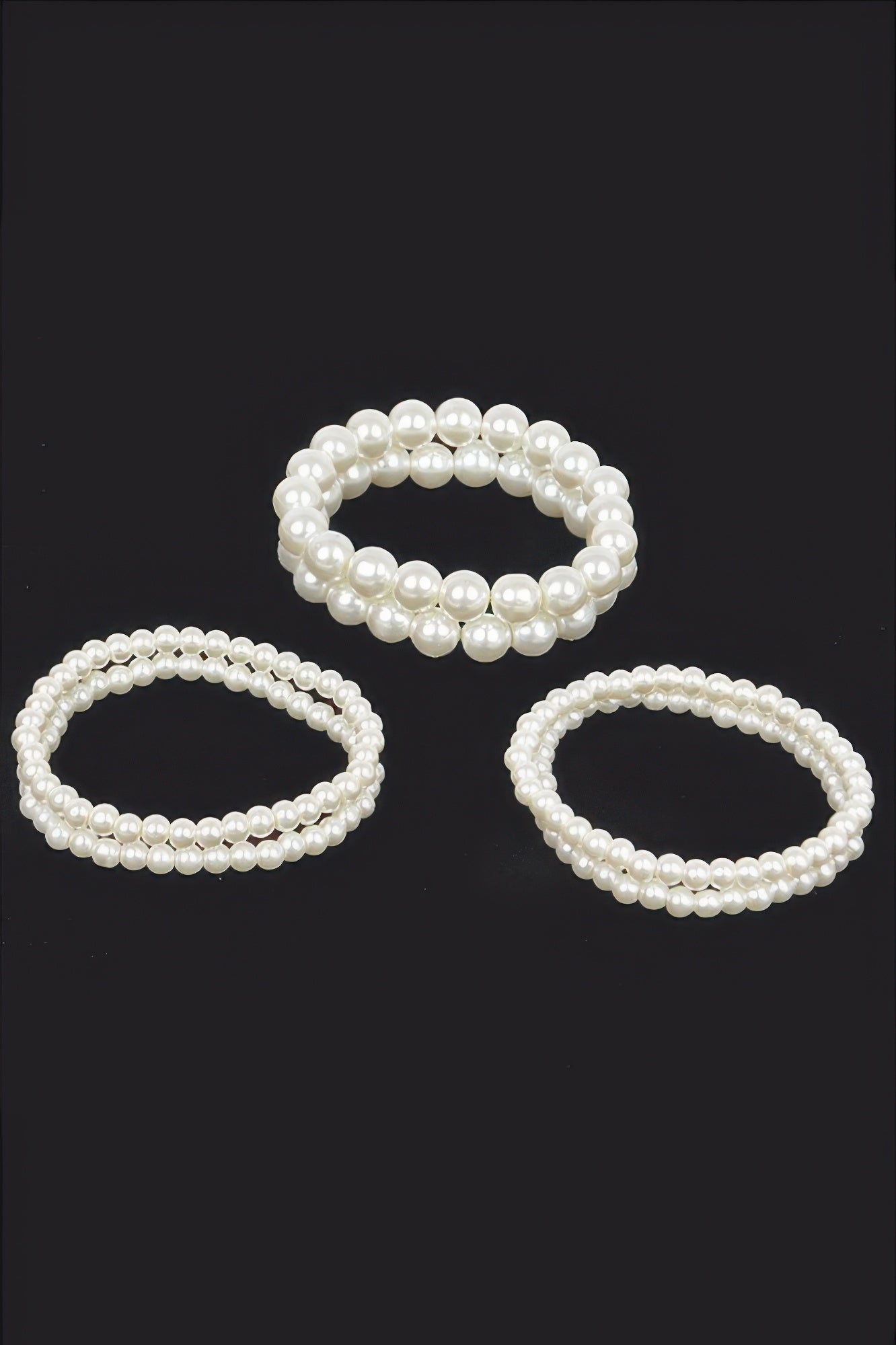 Cream faux pearl stretch bracelets set—three oval loops on a dark background