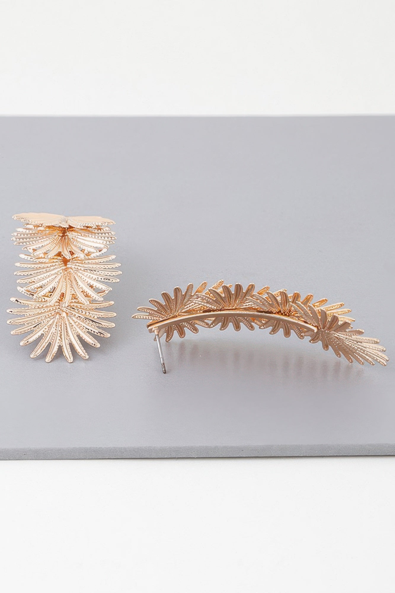 Gold multi-flare leaf drop earring, side view with curved metal bar back
