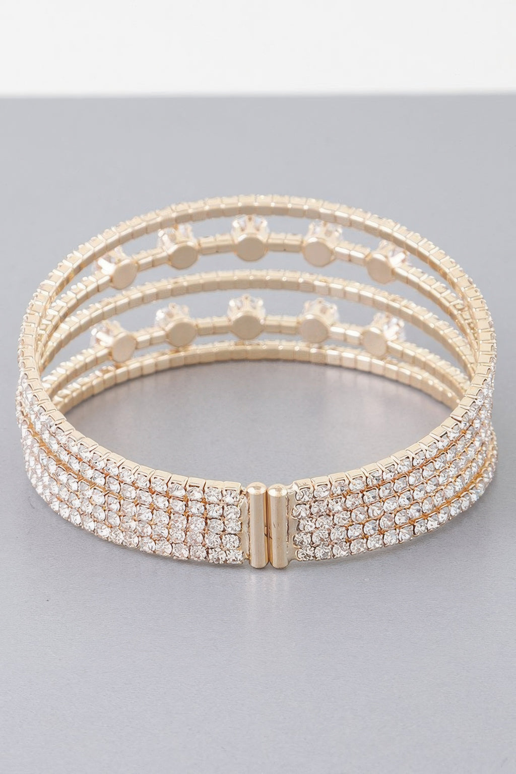 Gold-tone cuff bracelet with clear jeweled rows and center clasp detail