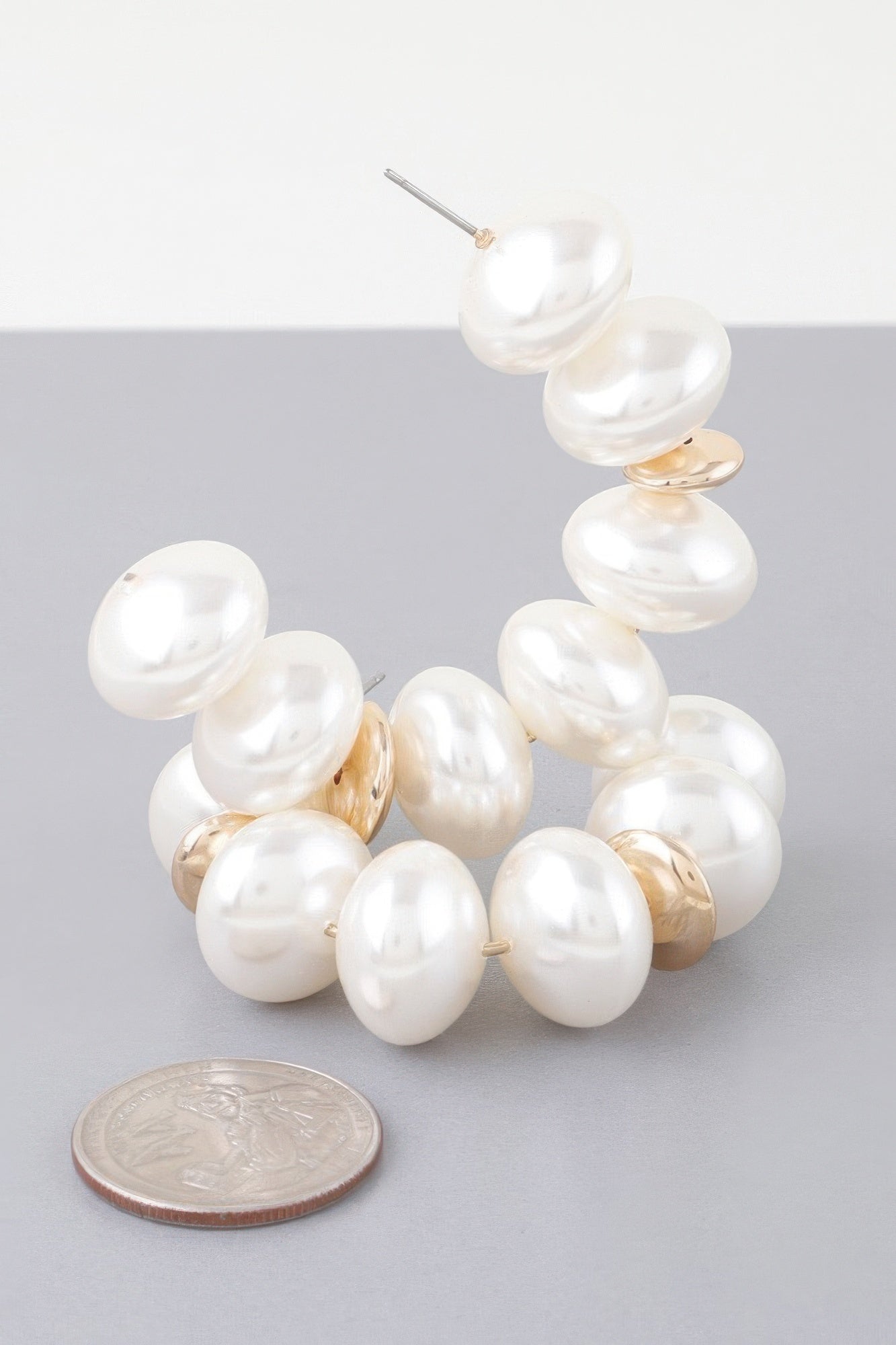 Close-up multi-oval pearl hoop earring with white pearls and gold accents