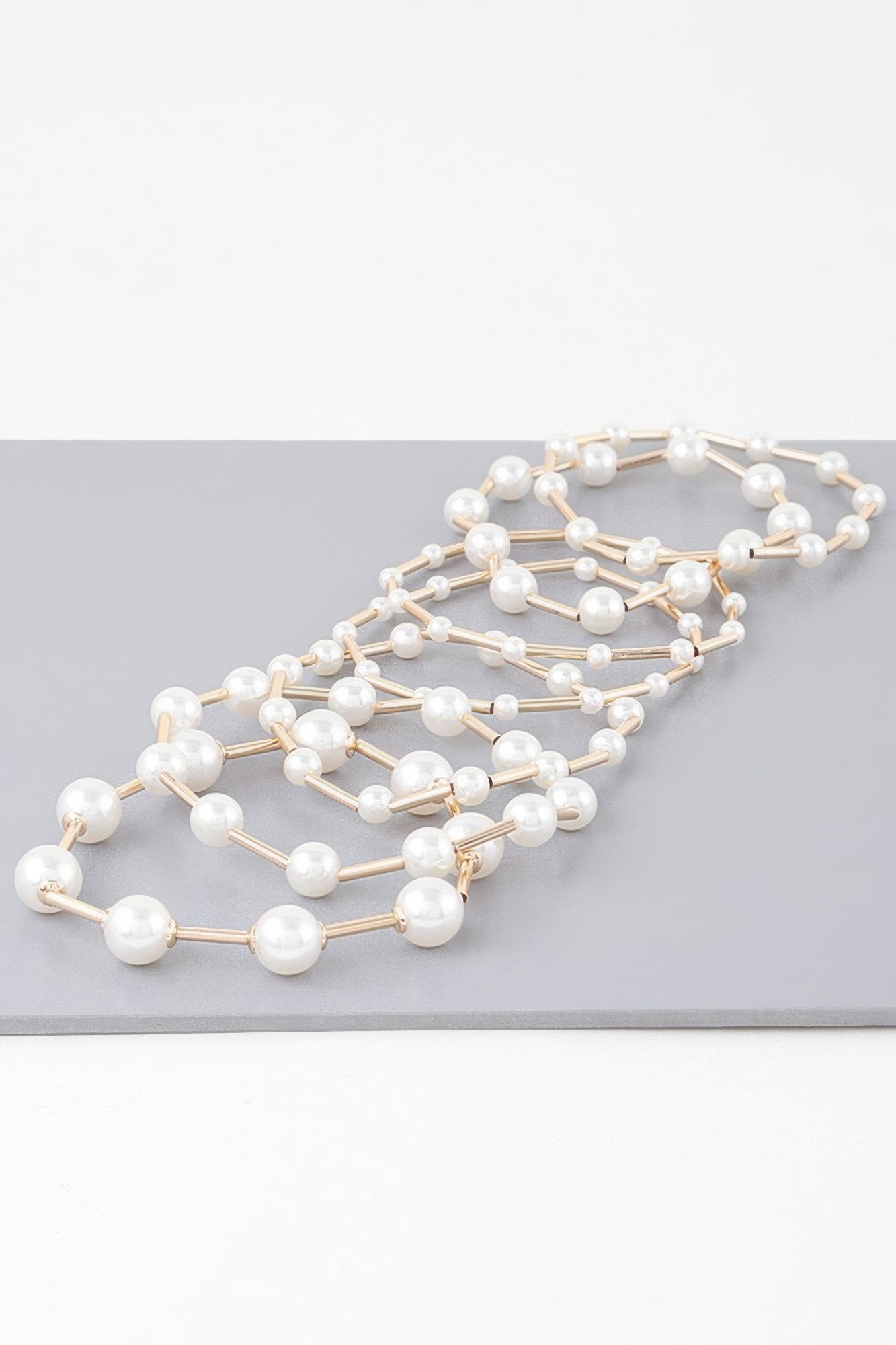 Multi pearl wire bracelet laid out, white pearls with gold-tone bar wire segments