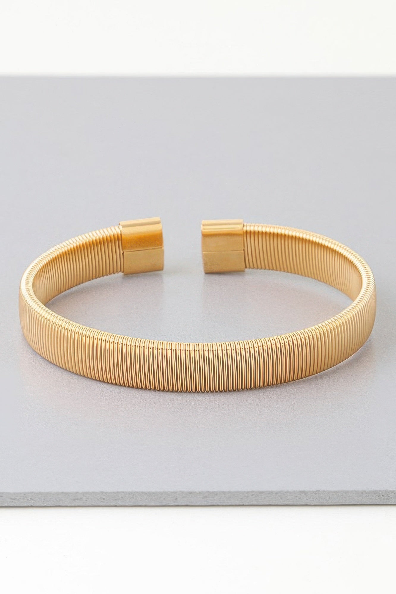 Gold ribbed cuff bracelet with two square clasp plates on top