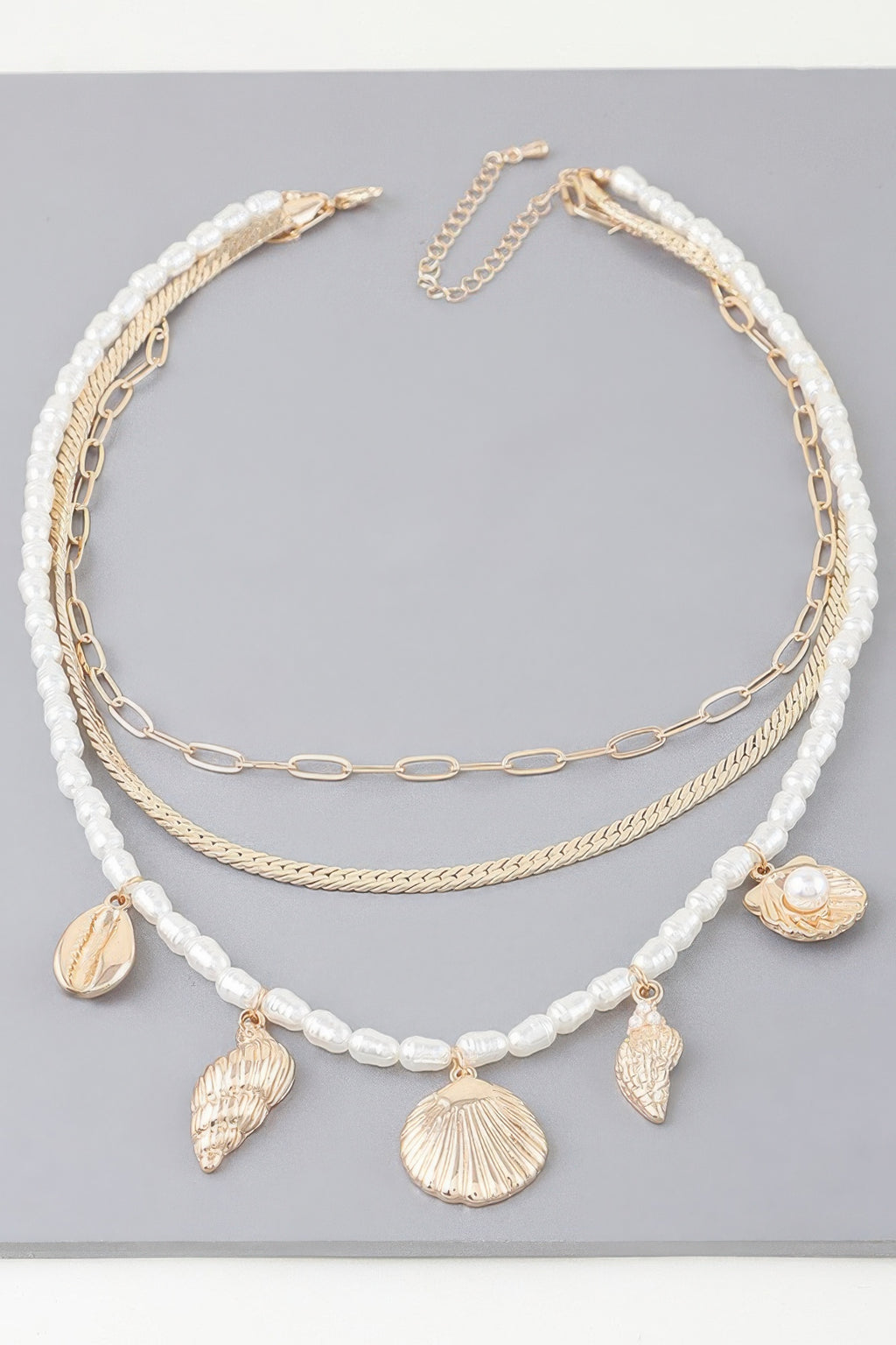 Layered necklace with white pearl-look beads, gold chain, and seashell charms