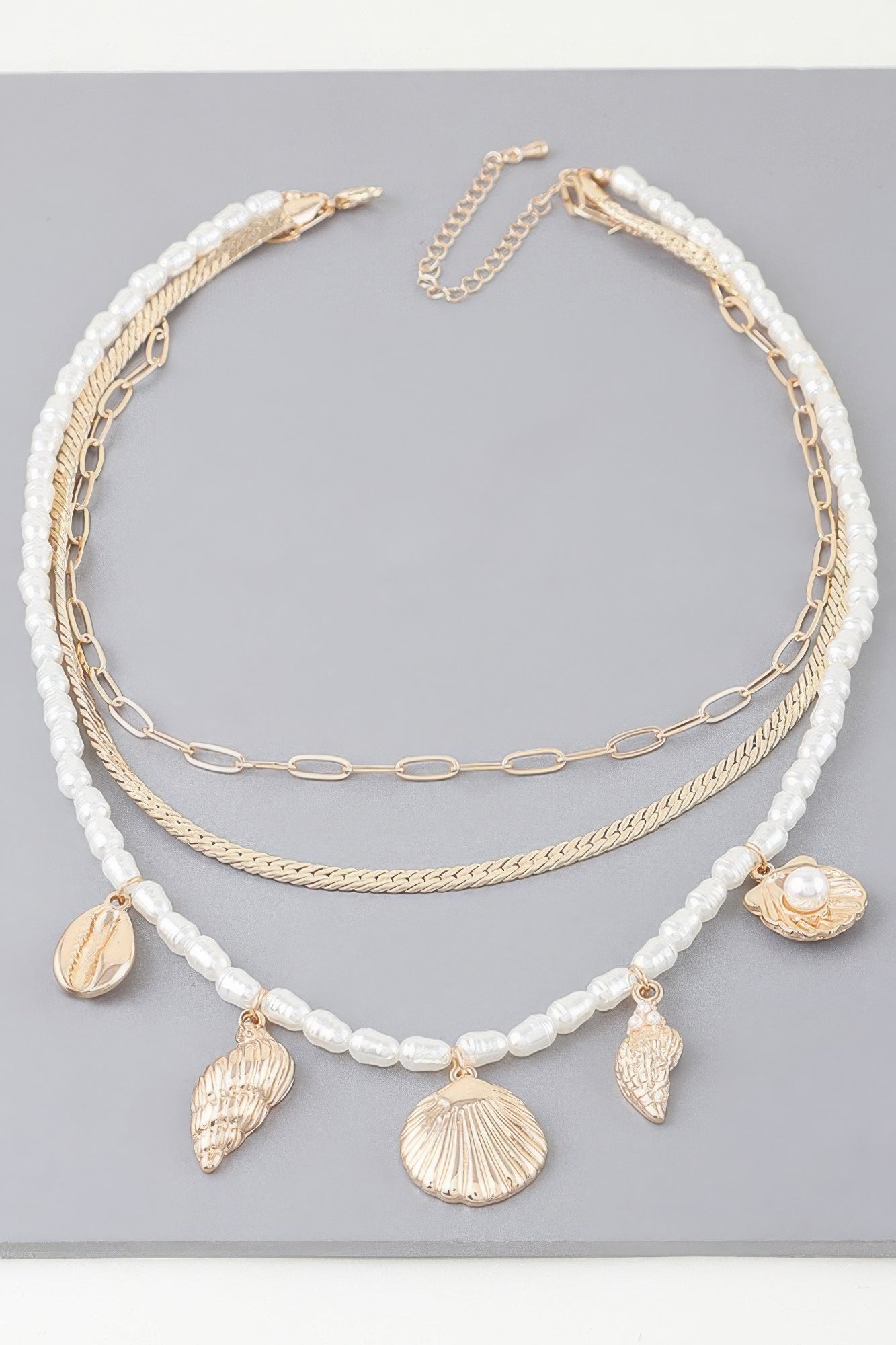 Layered necklace with white pearl-look beads, gold chain, and seashell charms