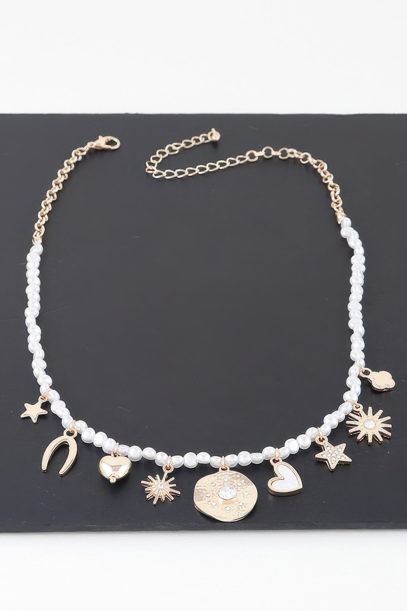 Beaded necklace featuring gold-tone charms: crescent moons, stars, hearts and coin charm