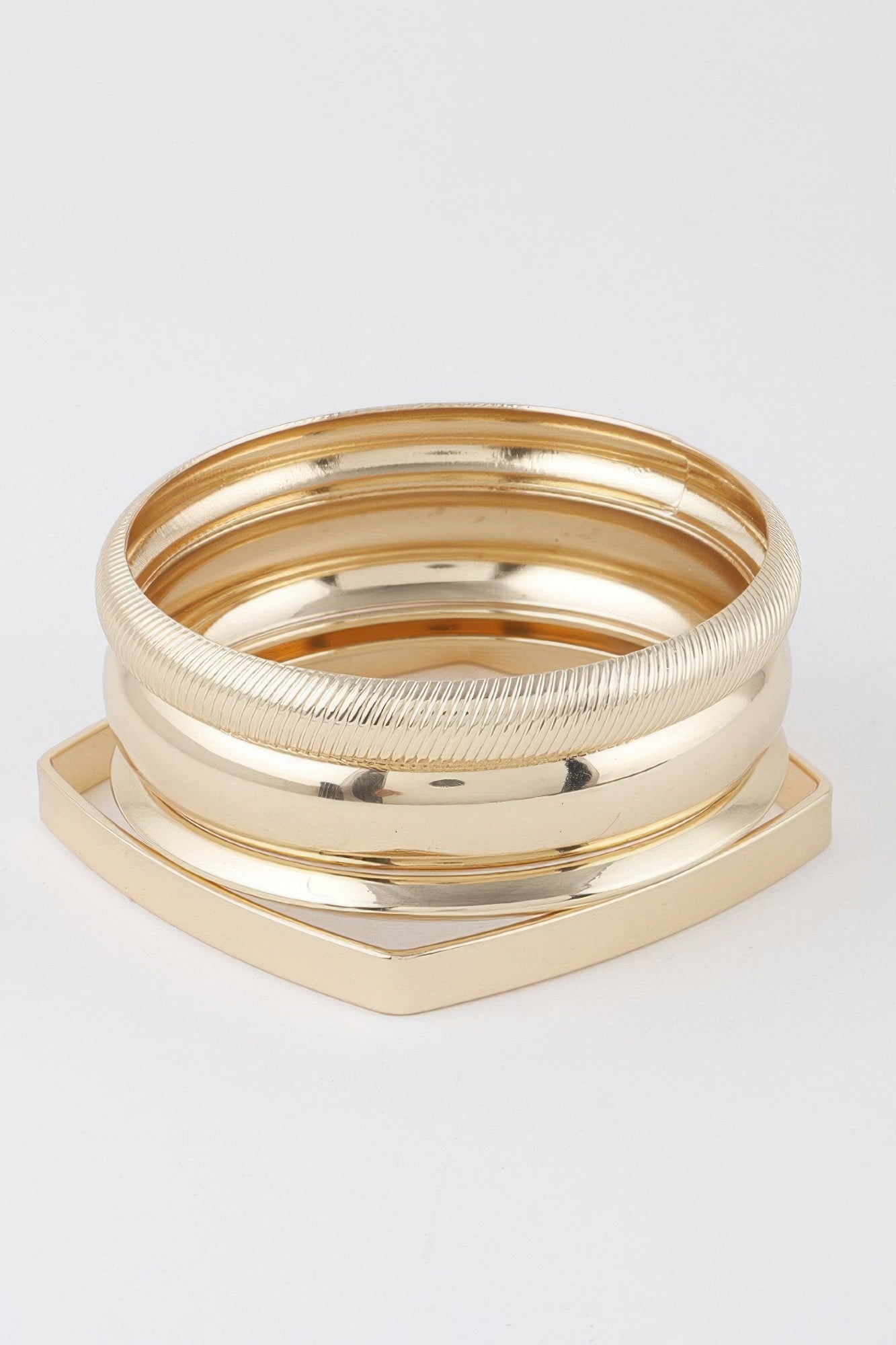 Gold multi-layer bracelet set with smooth and ridged bangles, geometric base