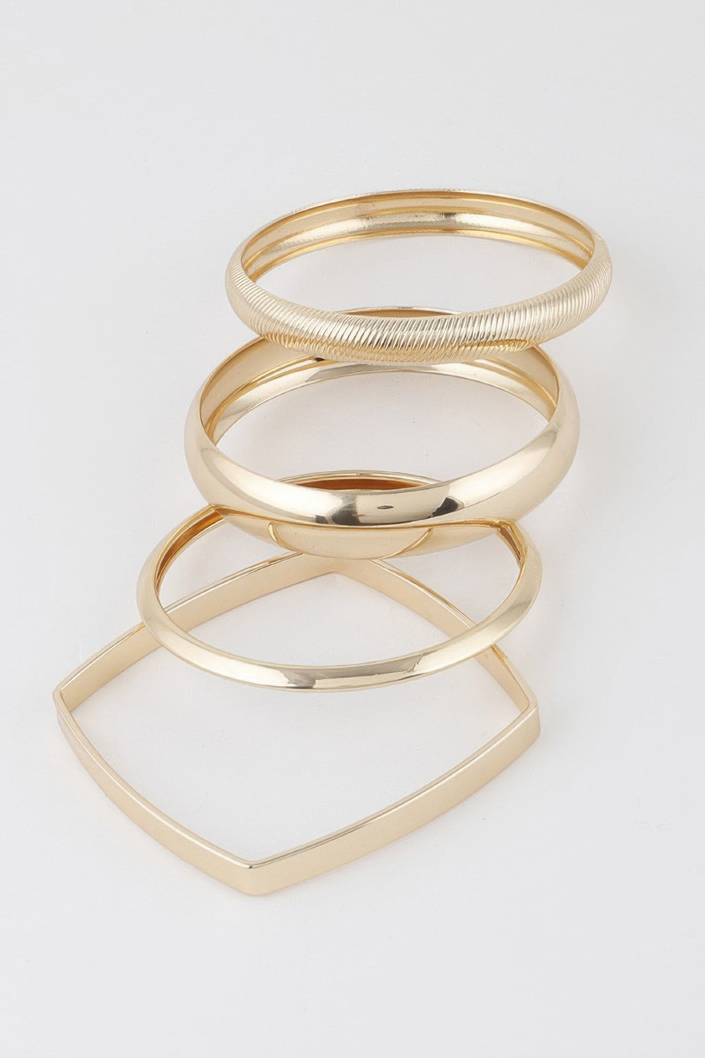 Gold stacked bangles with one ridged cuff and two polished rings