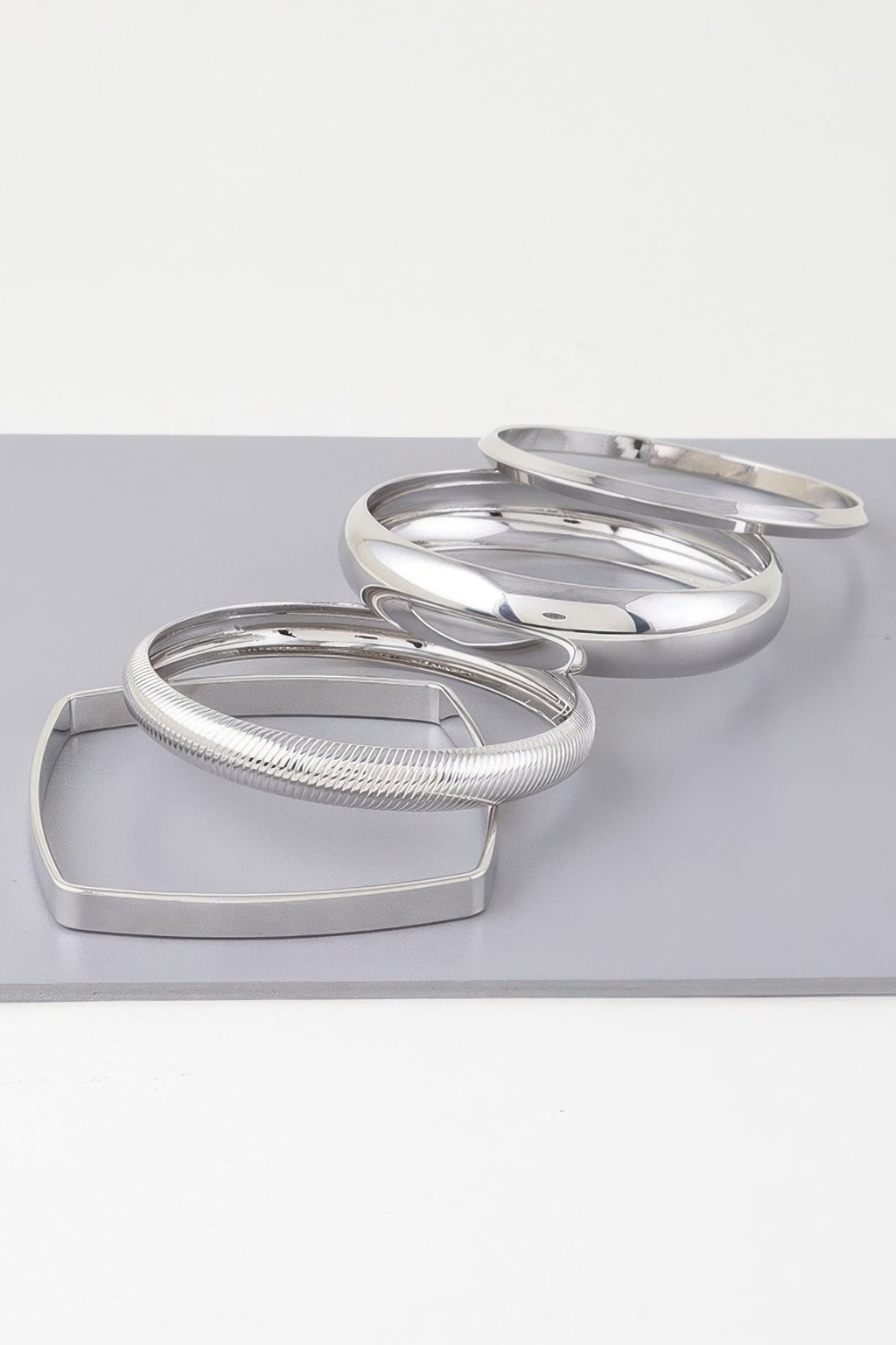 Silver layered bangles on rectangular display: ridged cuff and polished rings