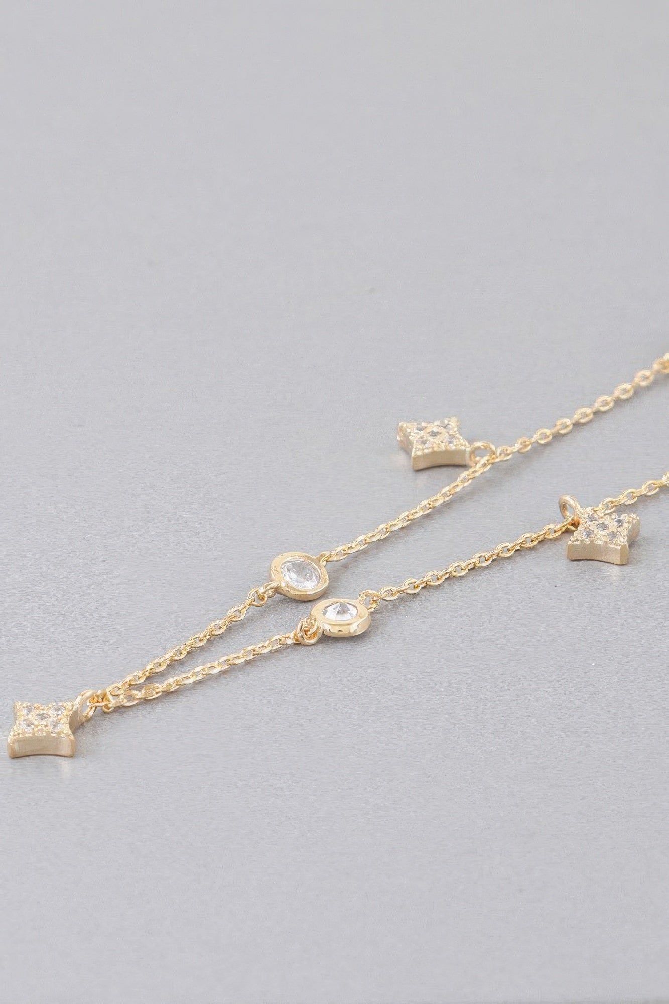 Gold-tone charm necklace with small star and heart links along the chain