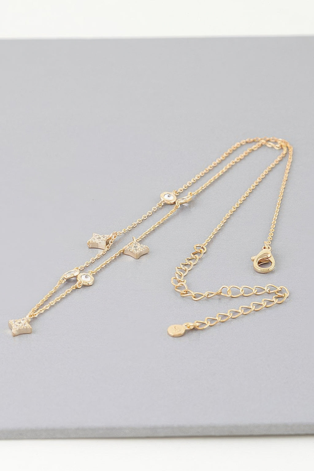 Gold charm necklace with multiple star, heart, and circular moon dangles