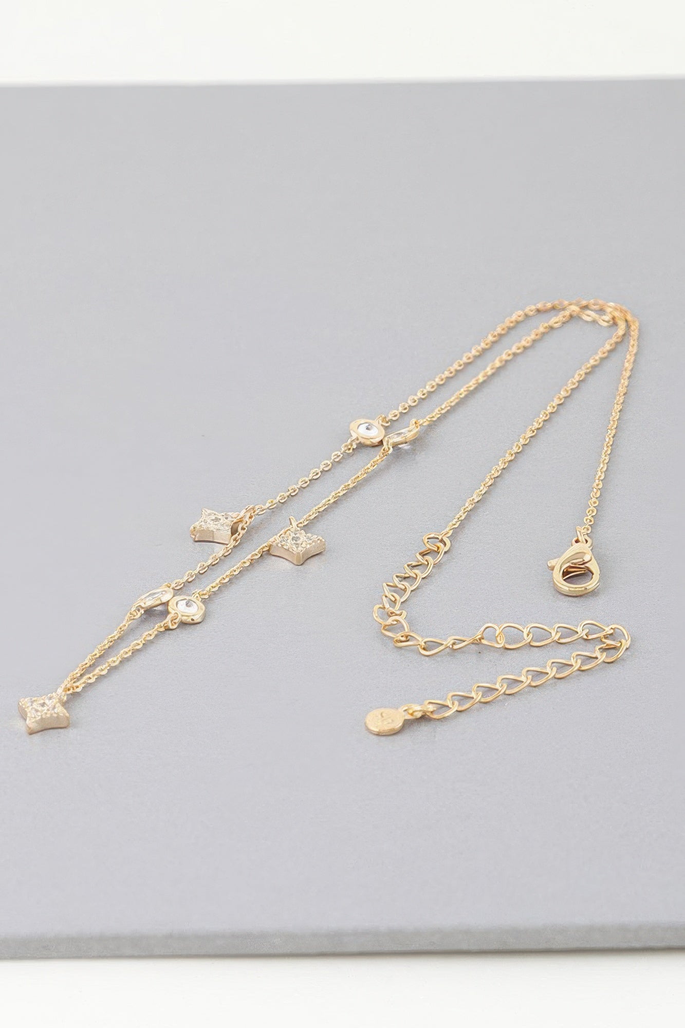 Gold charm necklace with multiple star, heart, and circular moon dangles