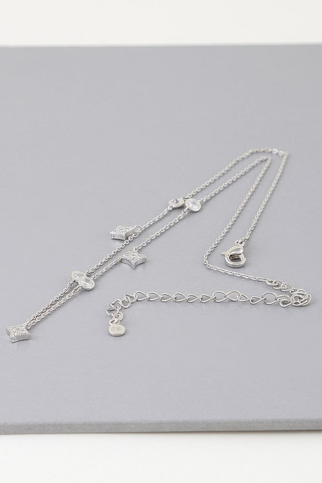 Silver-tone charm necklace with star, heart, and moon dangles on layered chains