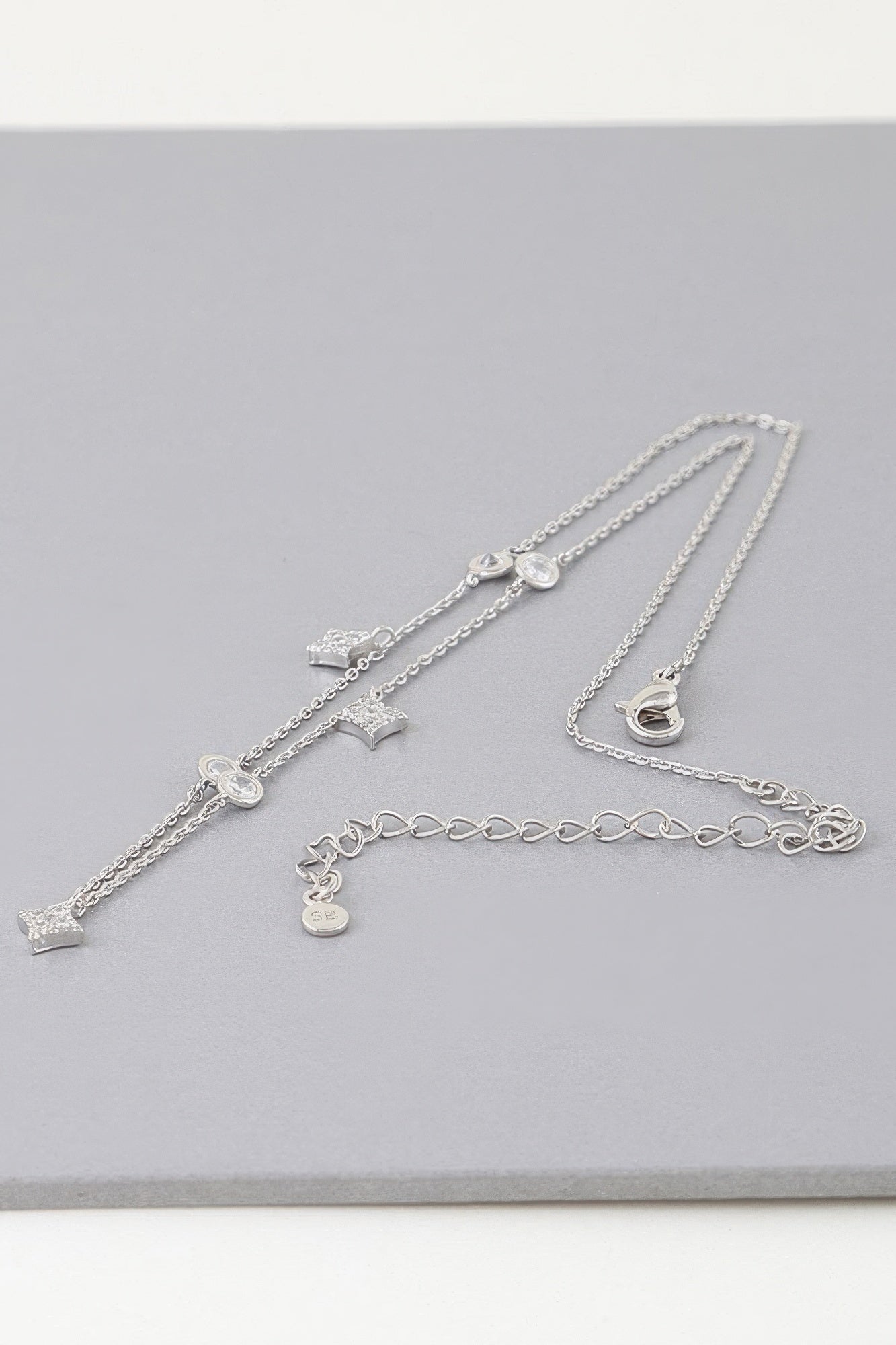 Silver-tone charm necklace with star, heart, and moon dangles on layered chains