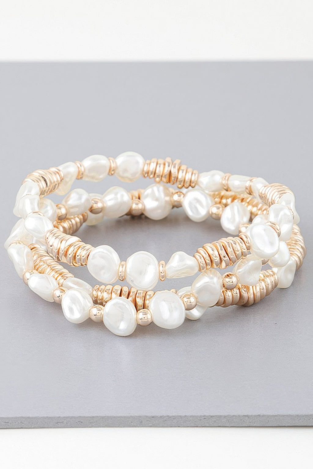 Set of three beaded bracelets: white pearls, gold-toned discs and rope accents