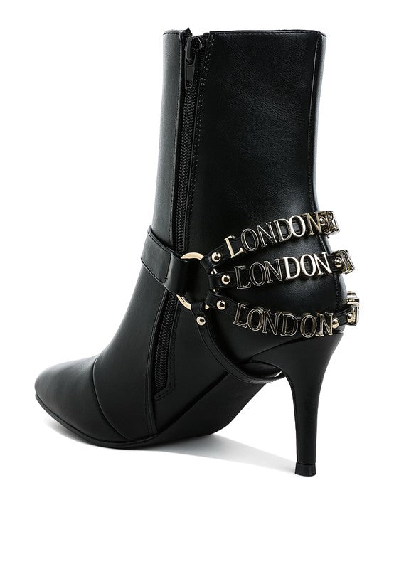 Black stiletto ankle boot with side zipper and layered “LONDON” harness straps