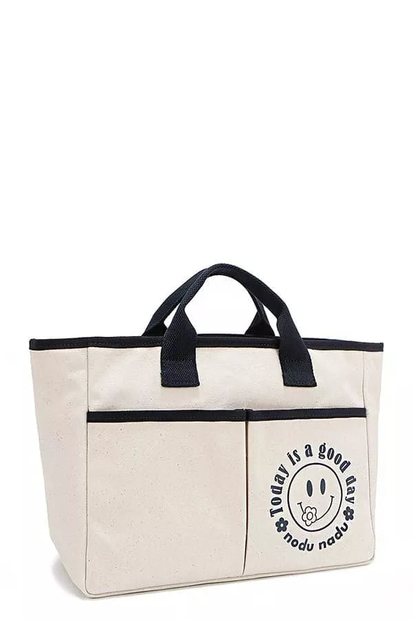 Beige canvas tote bag with black trim and side logo patch
