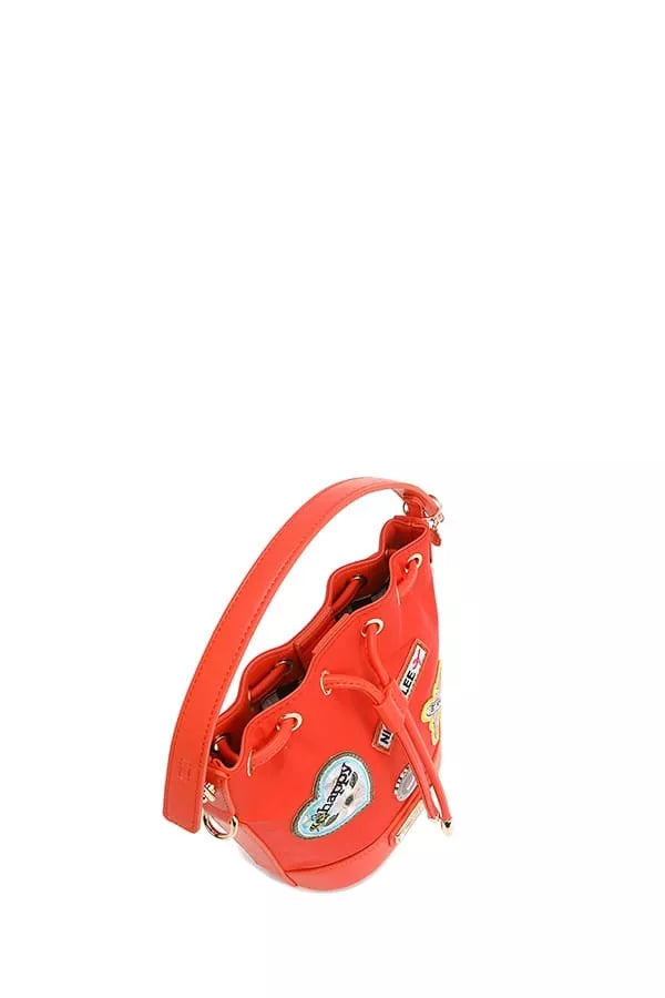 Red bucket bag angled view with front patches and dangling zipper pull hardware