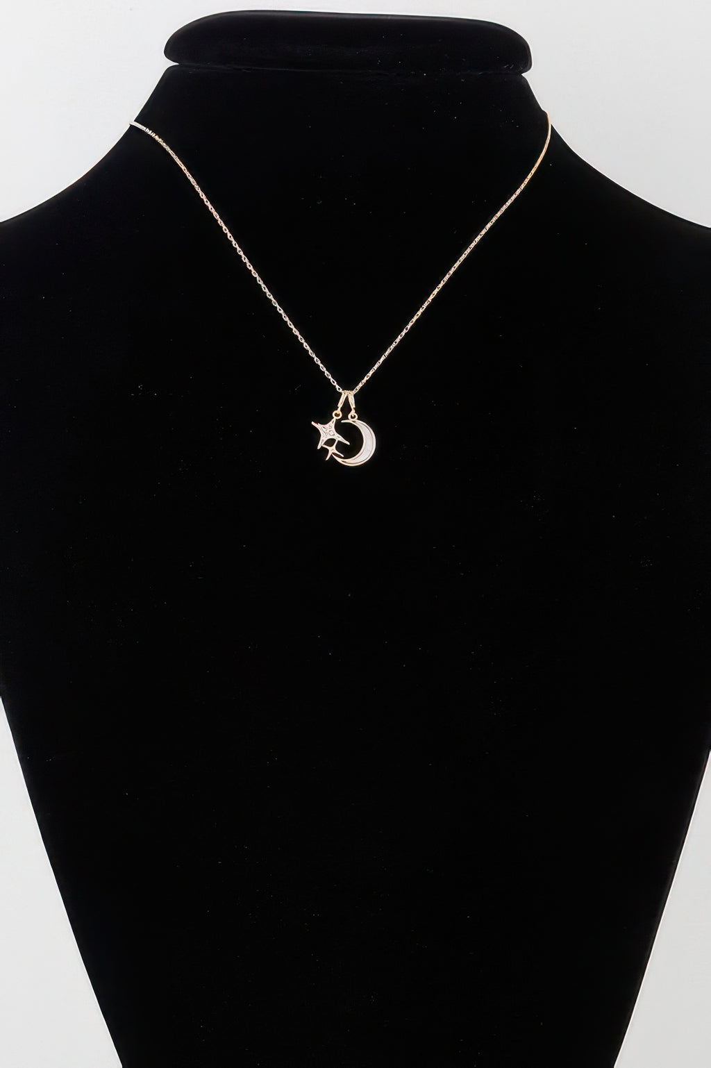 Gold moon-and-star pendant necklace on black display